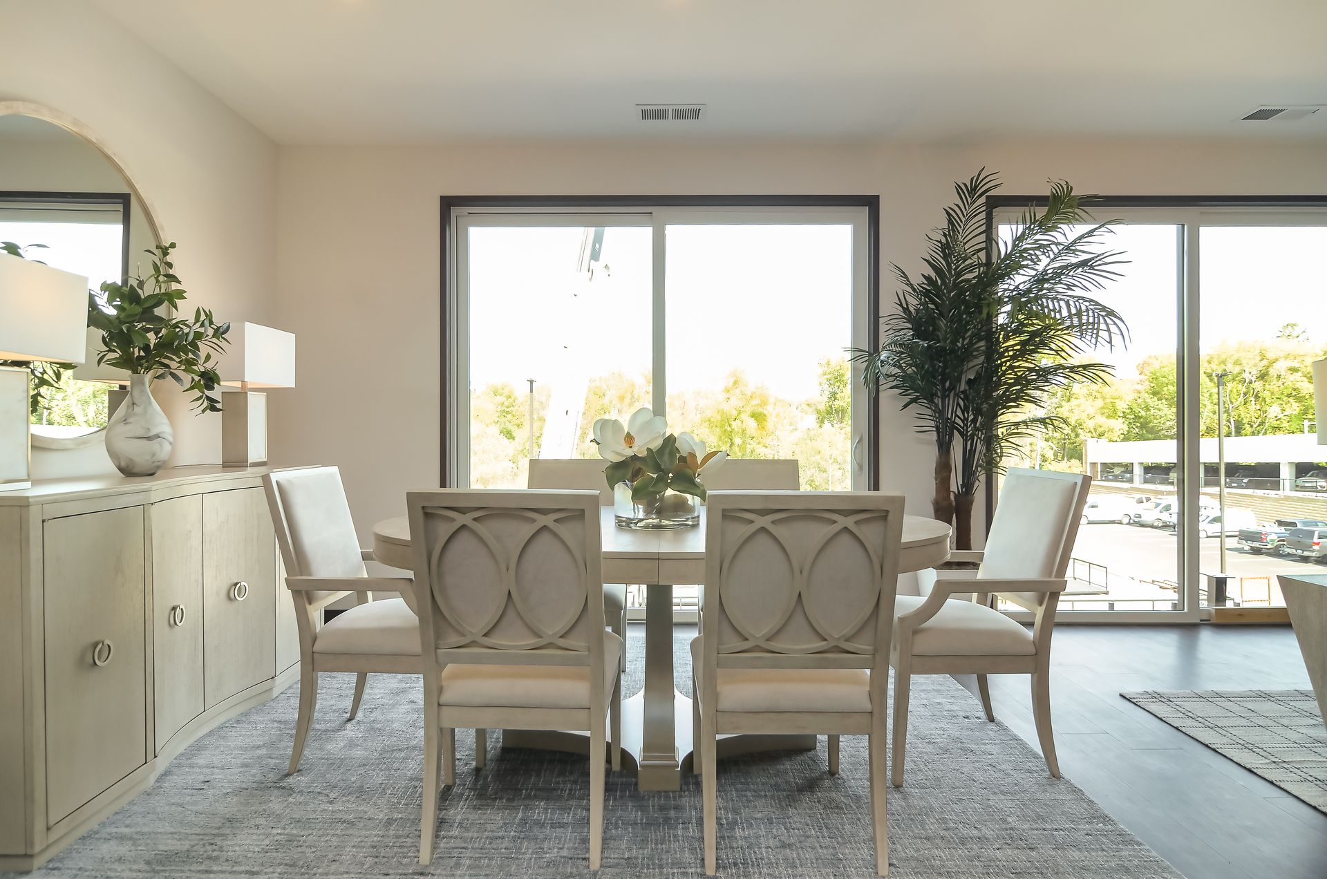 Dining room with a table, chairs, buffet, mirror, and large window overlooking trees at Ventana Apartments in Wayzata, MN.