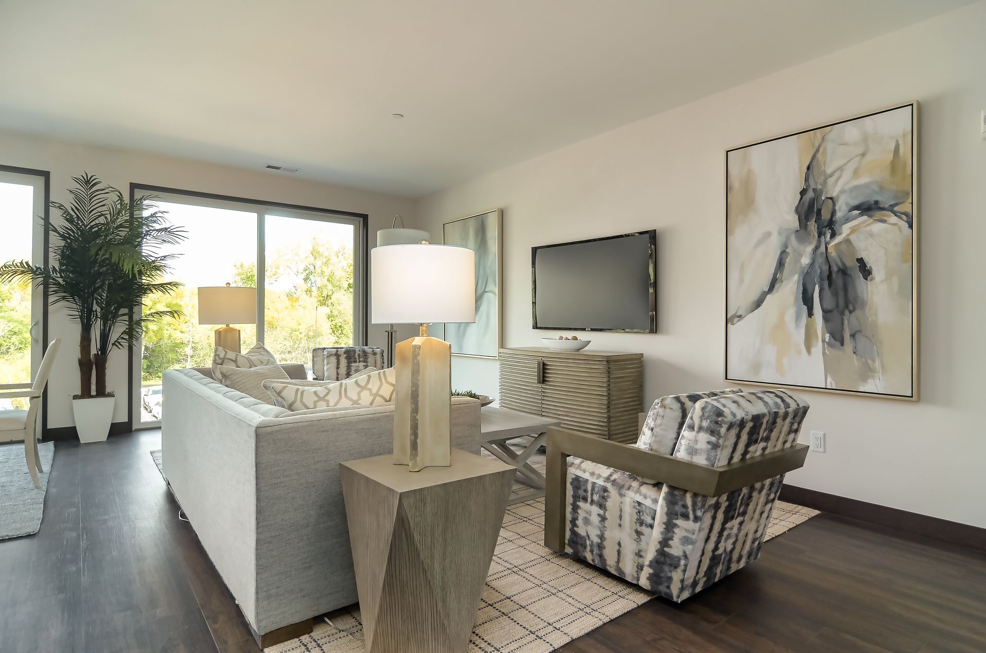 Modern living room with a couch, armchair, TV, and large abstract art at Ventana Apartments in Wayzata, MN.