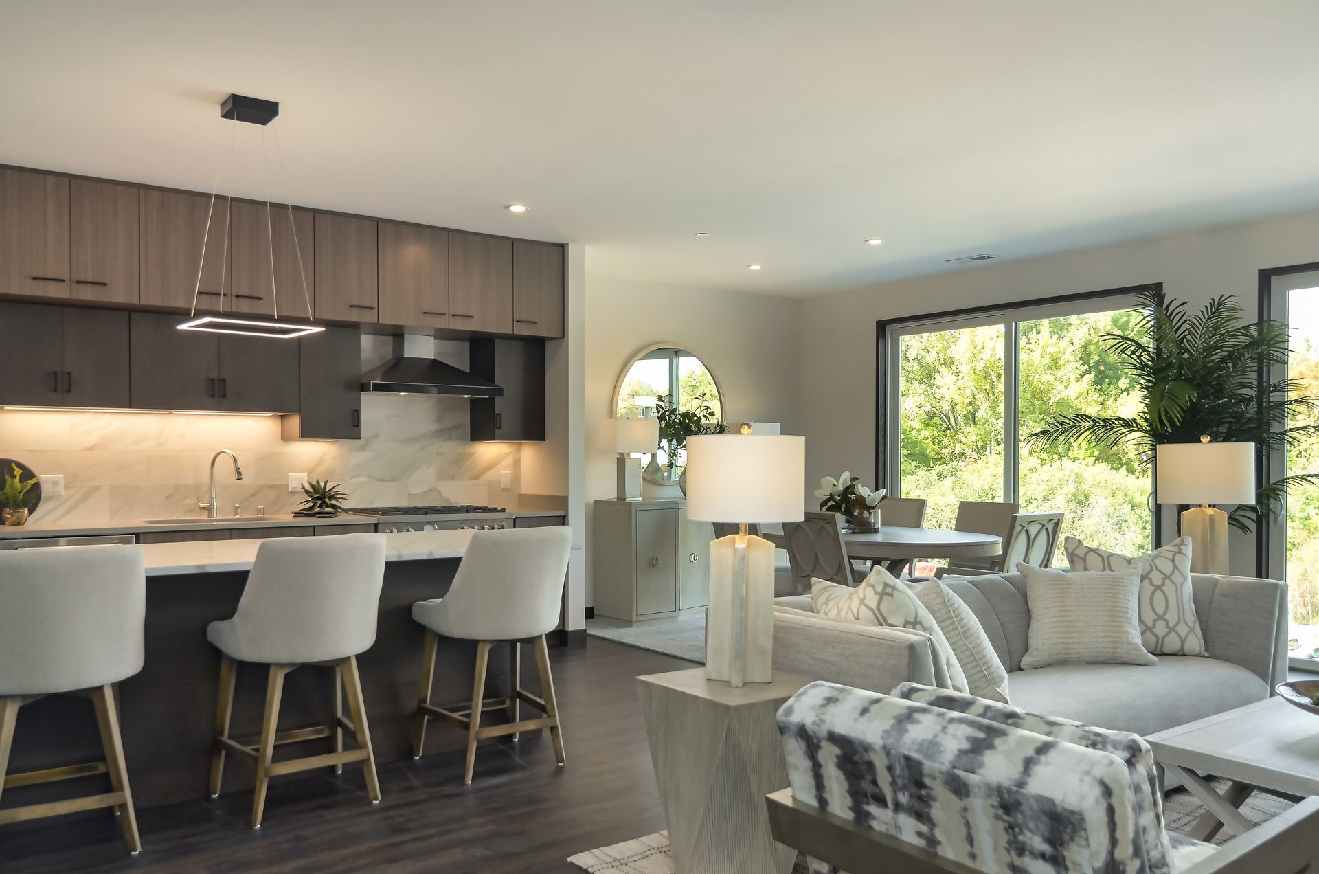 Modern open-concept living space with kitchen island, living room, and dining area overlooking a sunny exterior at Ventana Apartments in Wayzata, MN.
