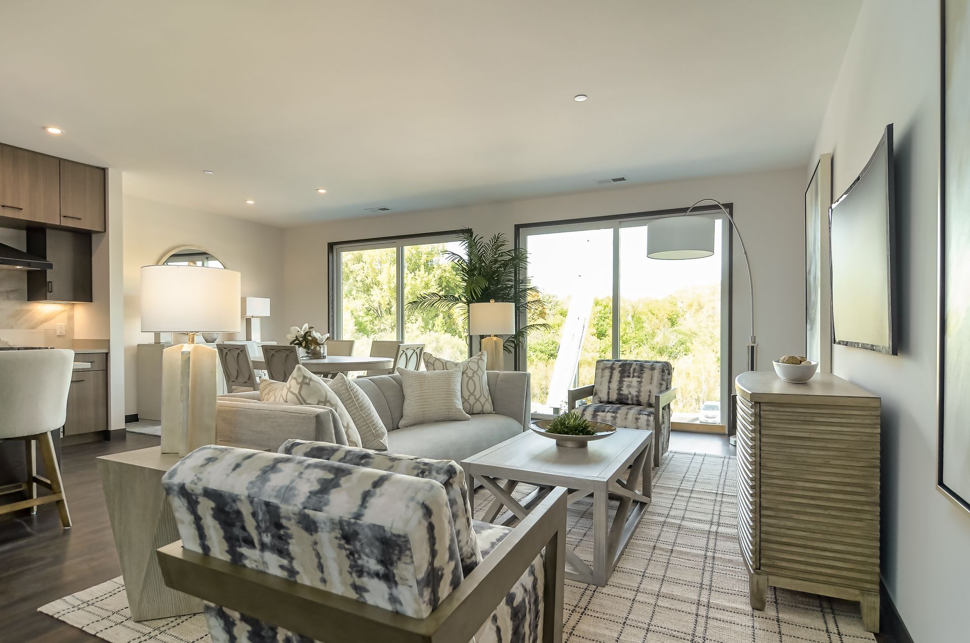 Living room with gray sofa, patterned armchairs, rug, and sliding glass doors at Ventana Apartments in Wayzata, MN.