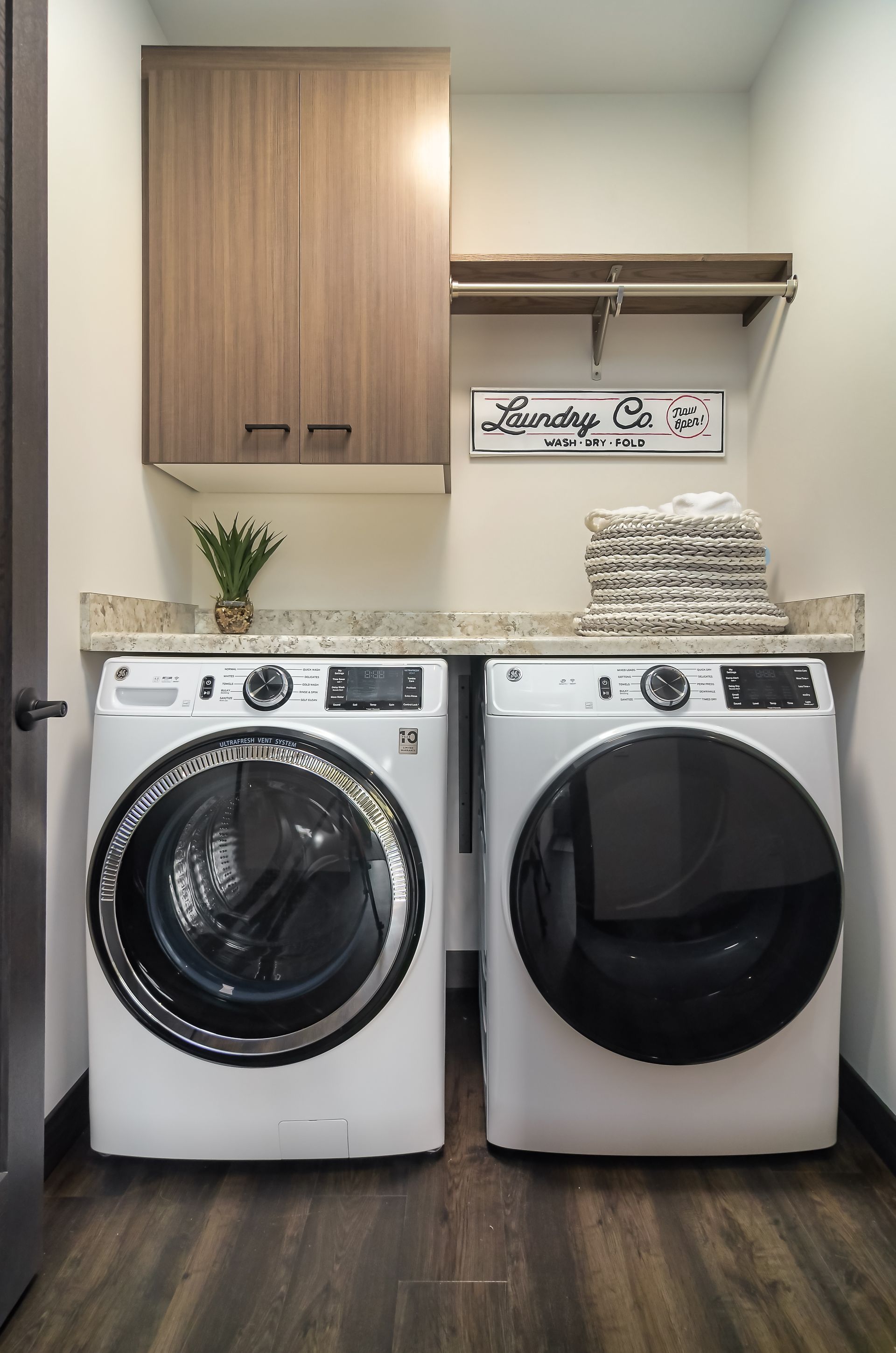Laundry room with a washer and dryer, countertop, cabinets, and shelving at Ventana Apartments in Wayzata, MN.