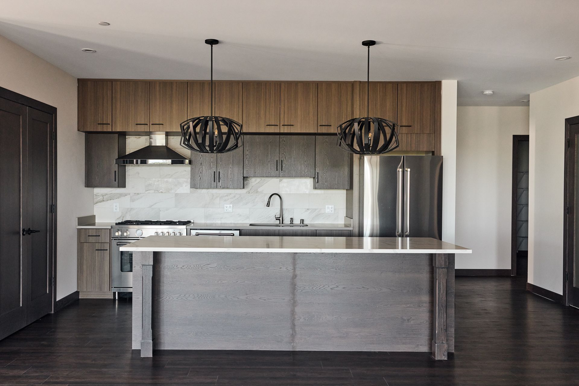 Modern kitchen with wood cabinets, stainless steel appliances, and dark island at Ventana Apartments in Wayzata, MN.
