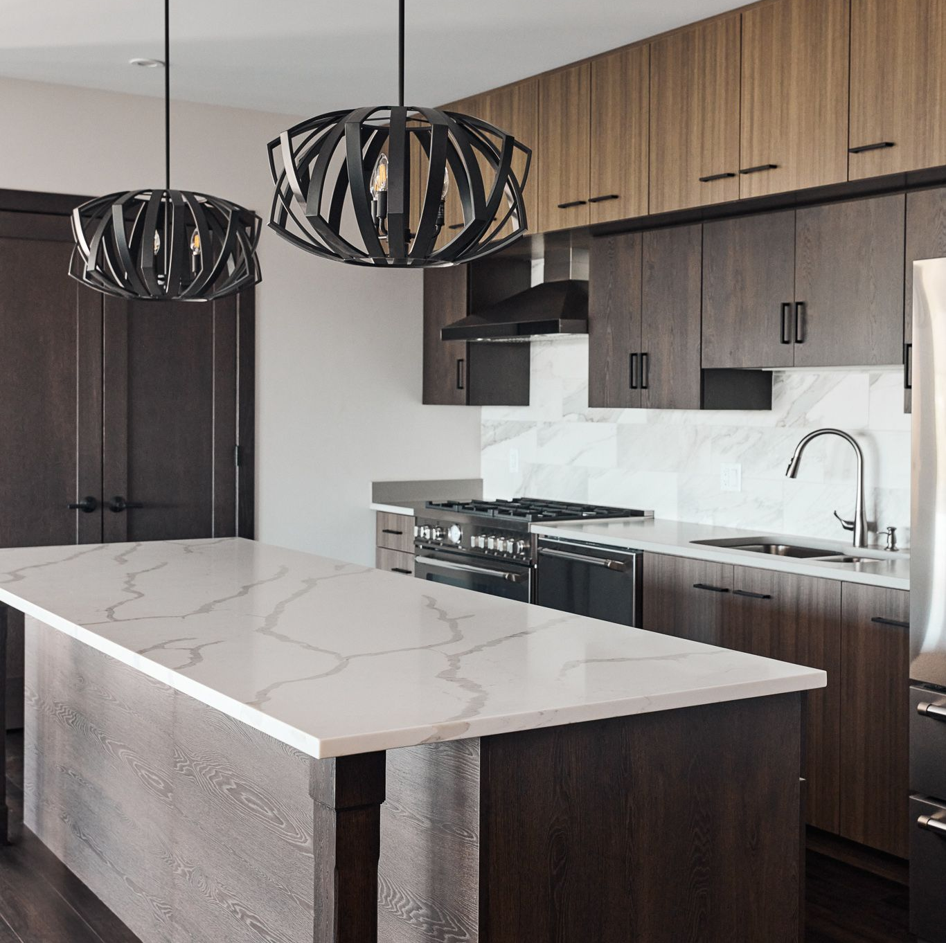 Modern kitchen with dark cabinetry, white countertop, and pendant lights at Ventana Apartments in Wayzata, MN.