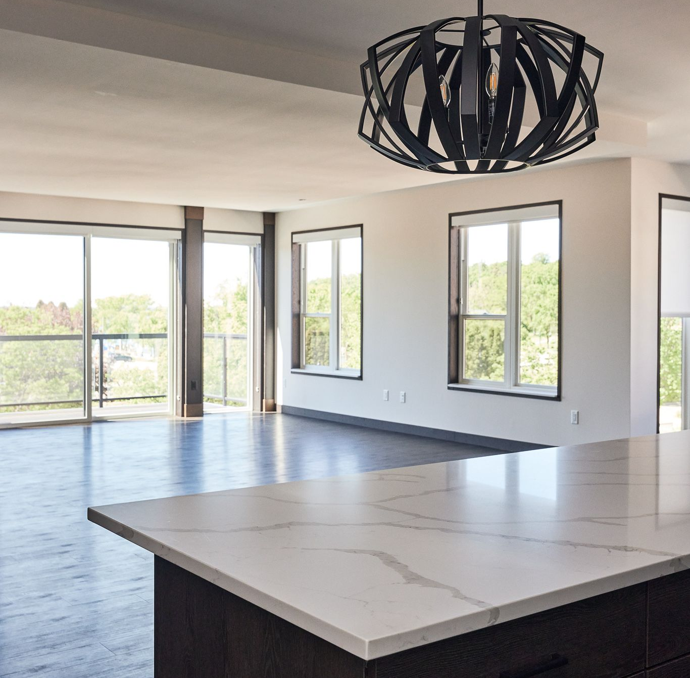 Modern kitchen interior with white countertops, wooden cabinets, and large windows at Ventana Apartments in Wayzata, MN.