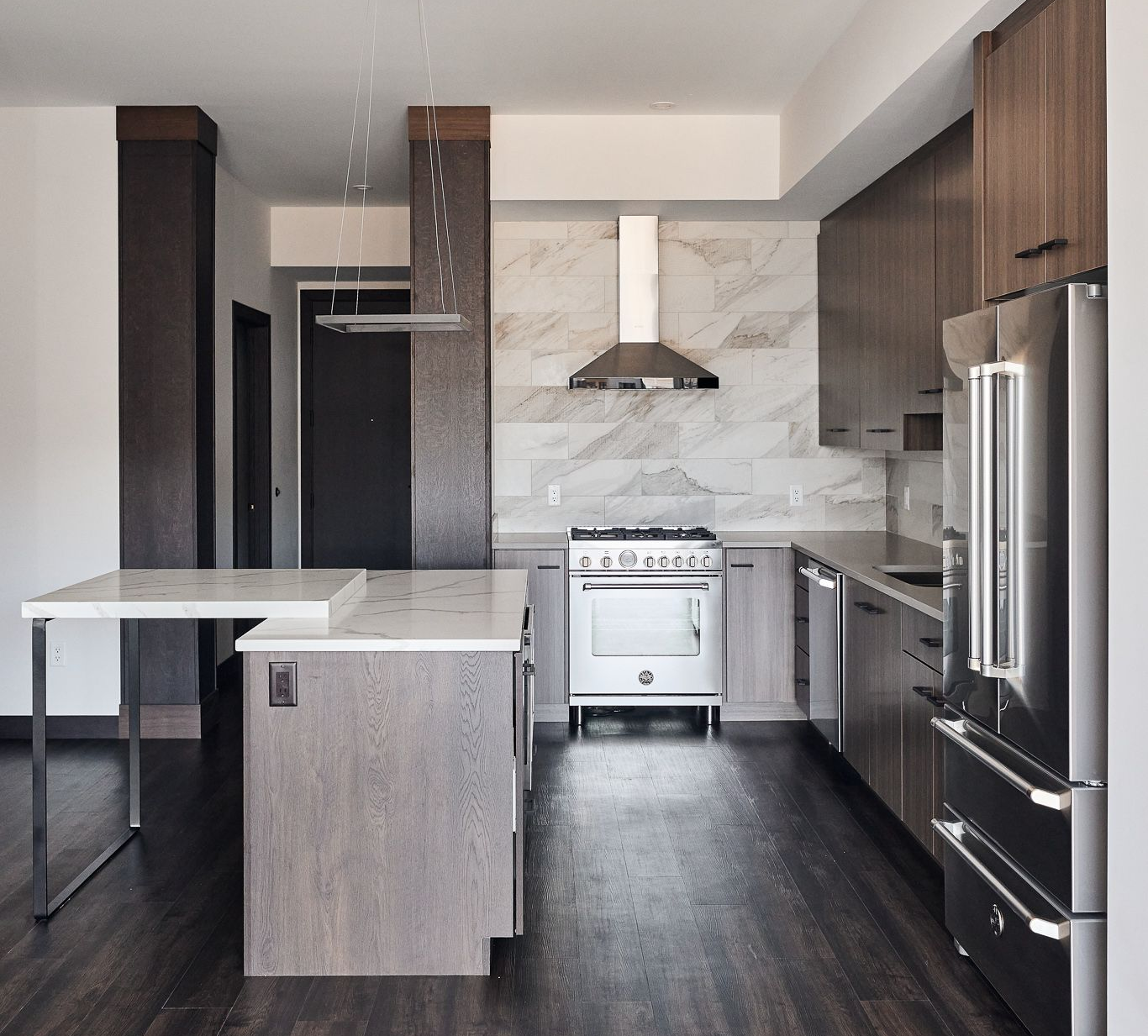 Modern kitchen with wood cabinets, stainless steel appliances, marble island, and dark wood floor at Ventana Apartments in Wayzata, MN.