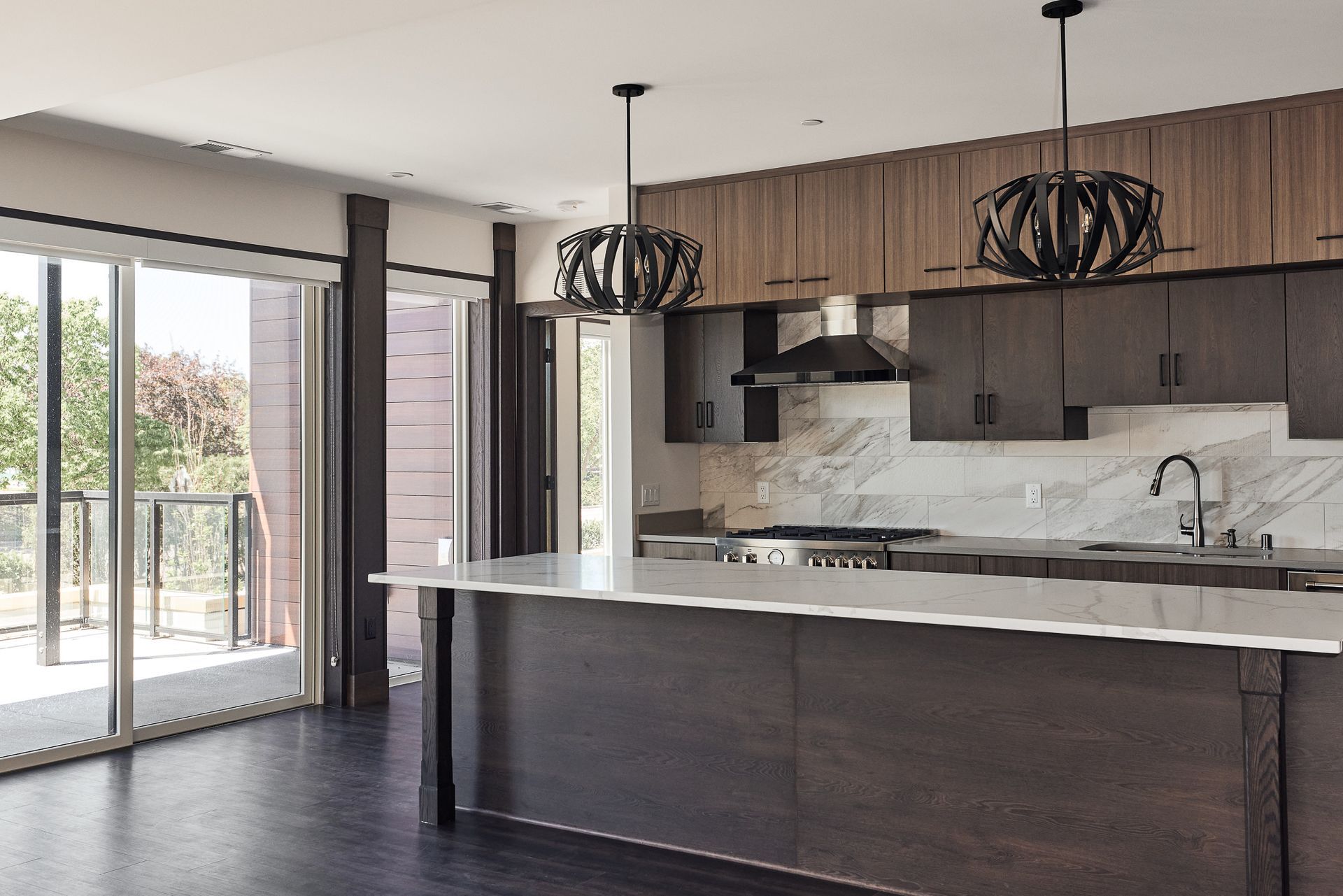 Modern kitchen with island, dark wood cabinetry, marble backsplash, and large windows at Ventana Apartments in Wayzata, MN.