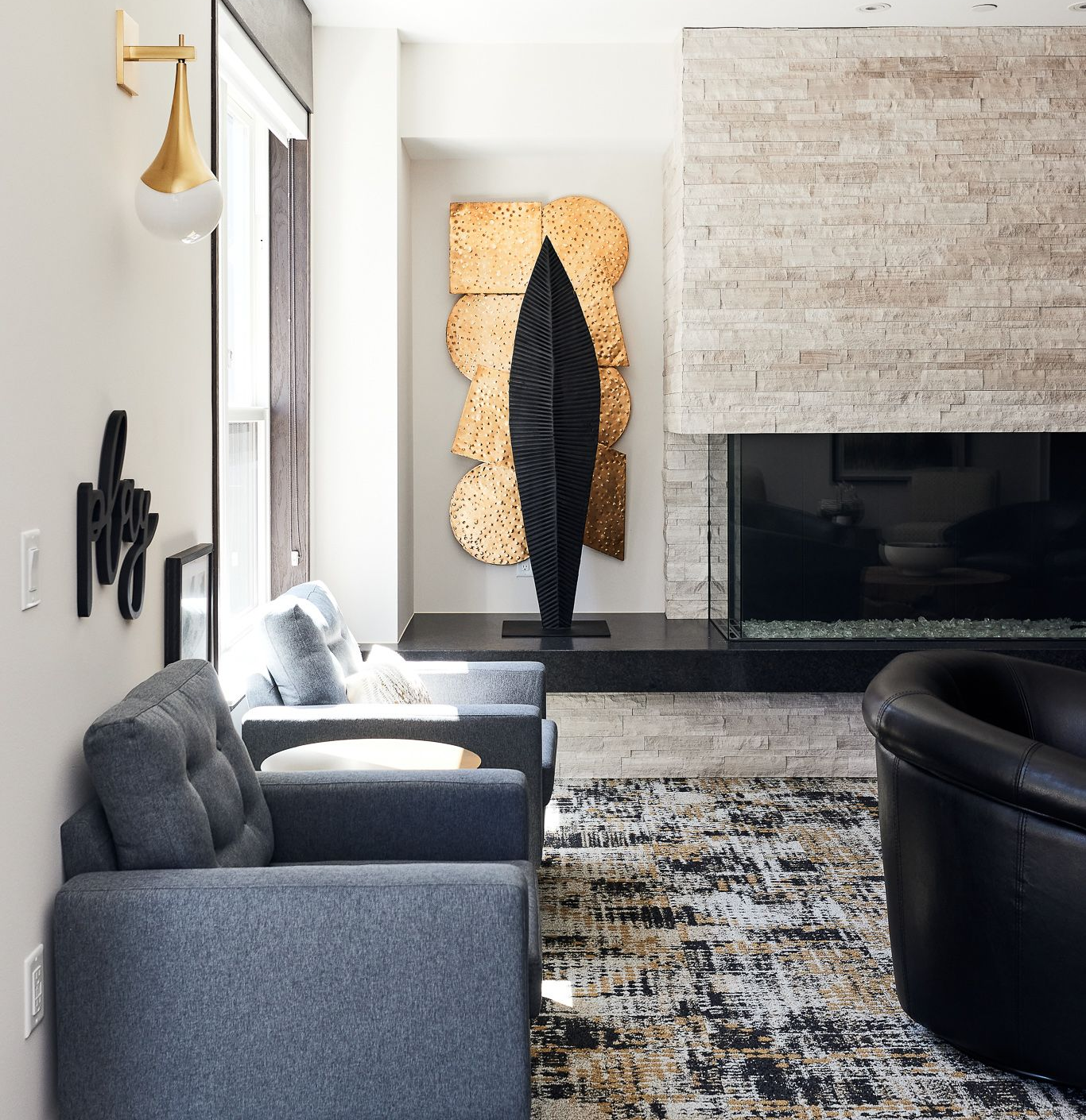 Living room with modern art, gray couches, fireplace, and patterned rug at Ventana Apartments in Wayzata, MN.