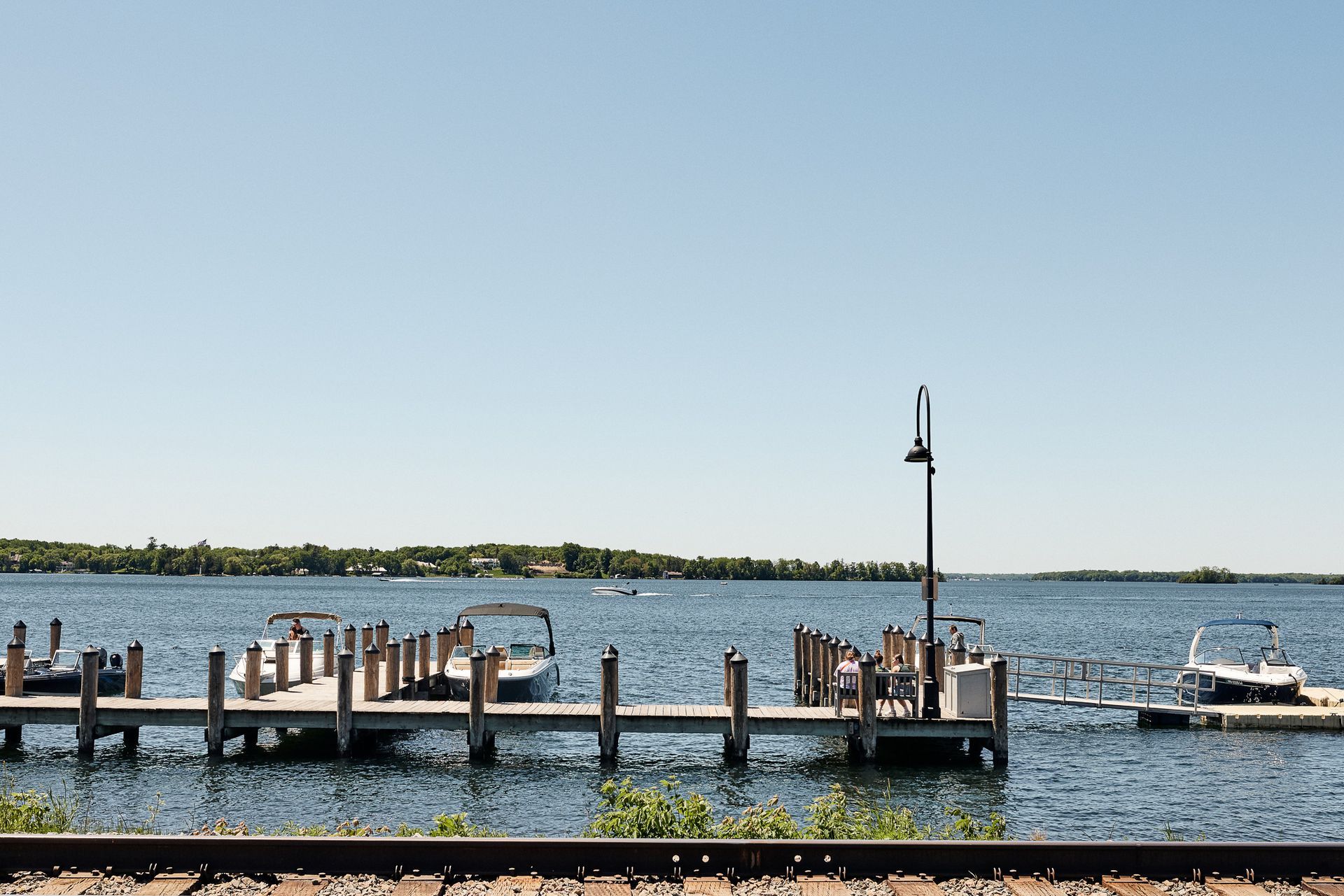 Wooden docks on a lake with boats, under a clear blue sky.