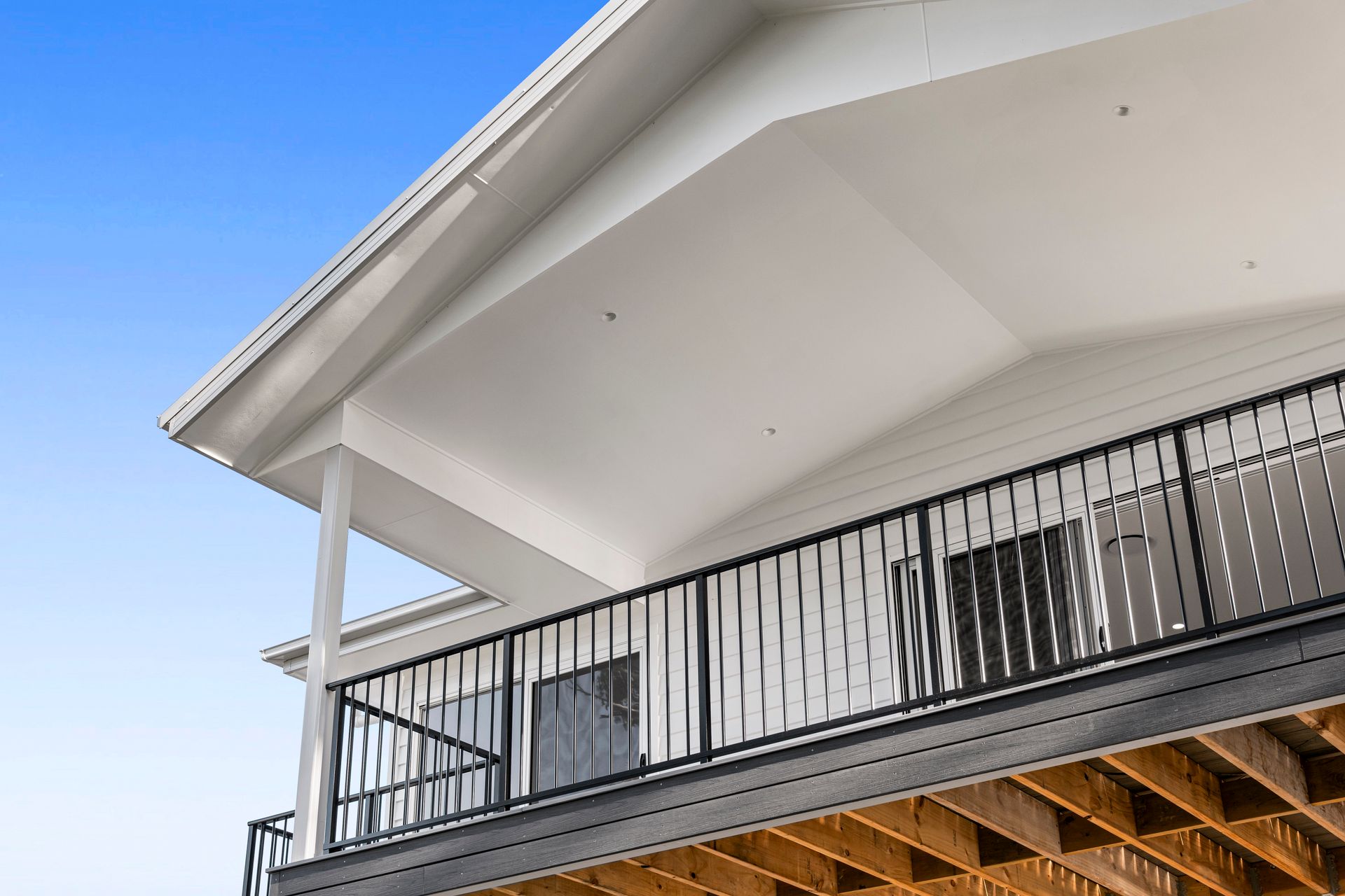 White and Black House Exterior with A Balcony, Black Railing, and Blue Sky — Designer Building Pty Ltd In Charmhaven, NSW