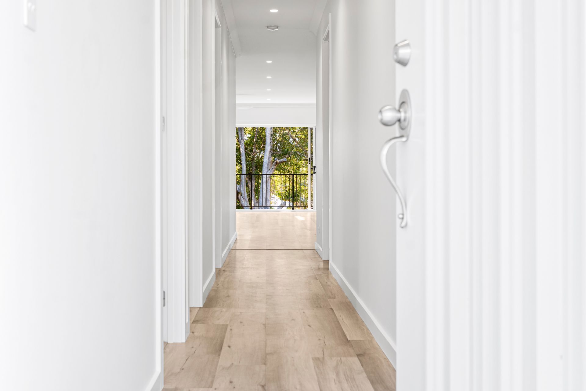 Hallway with White Walls, Wood Floor, and View of Outdoors at The End — Designer Building Pty Ltd In Budgewoi, NSW