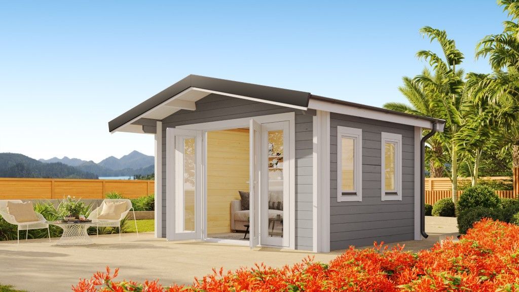 Grey Wooden Cabin With Glass Doors and Windows, Set in a Garden With Chairs, Flowers, and Mountains in the Distance — Designer Building Pty Ltd In Charmhaven, NSW