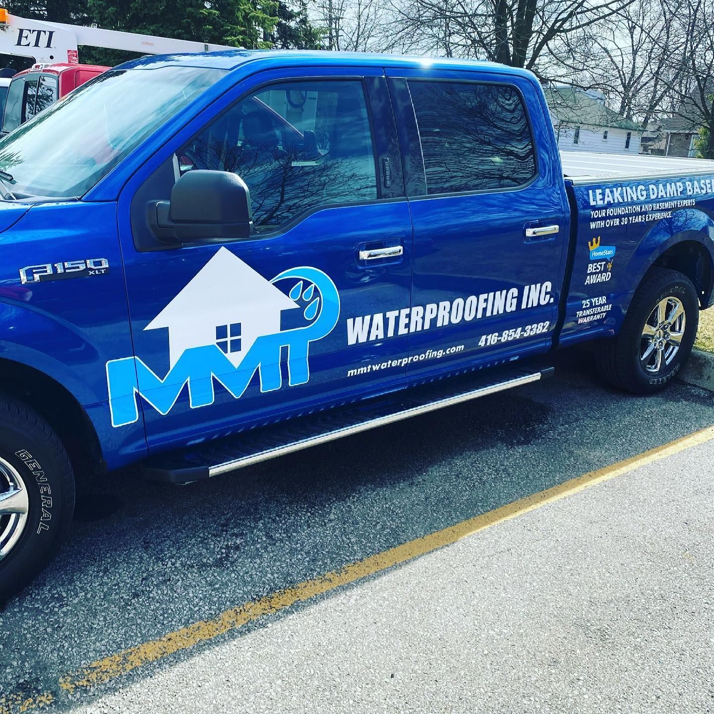 Blue MMP Waterproofing Inc. truck parked on a road. White logo with a house and water.