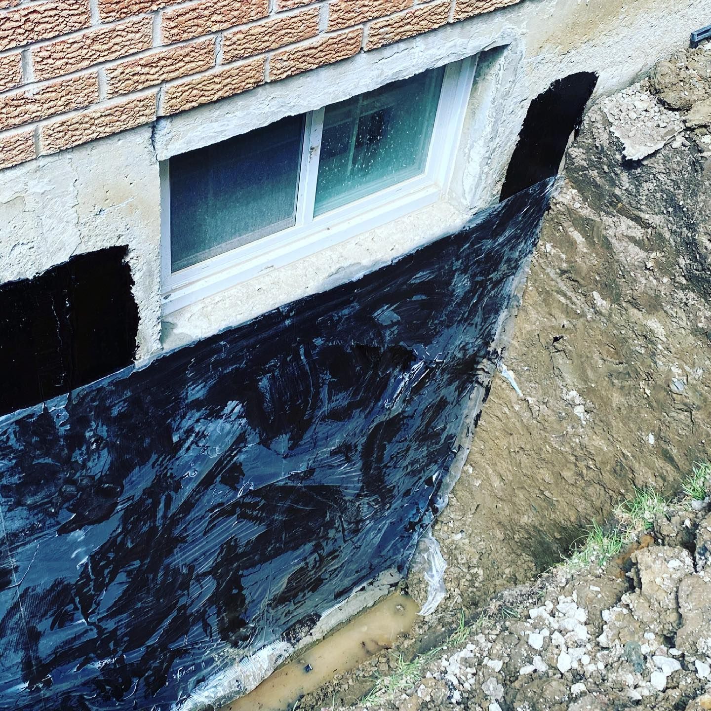 A brick wall with a window and a black tarp on it