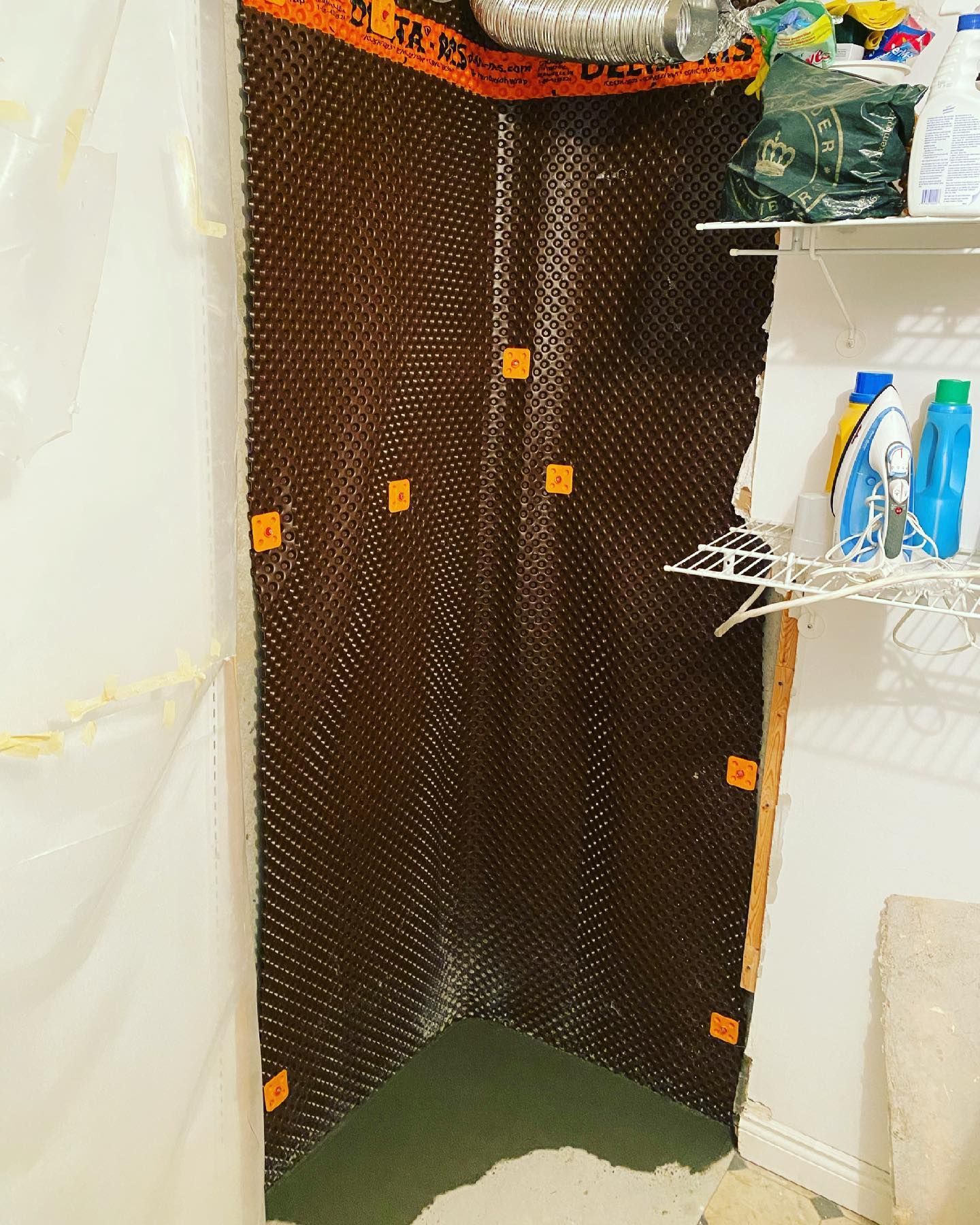 A corner of a laundry room with a drain board on the wall.