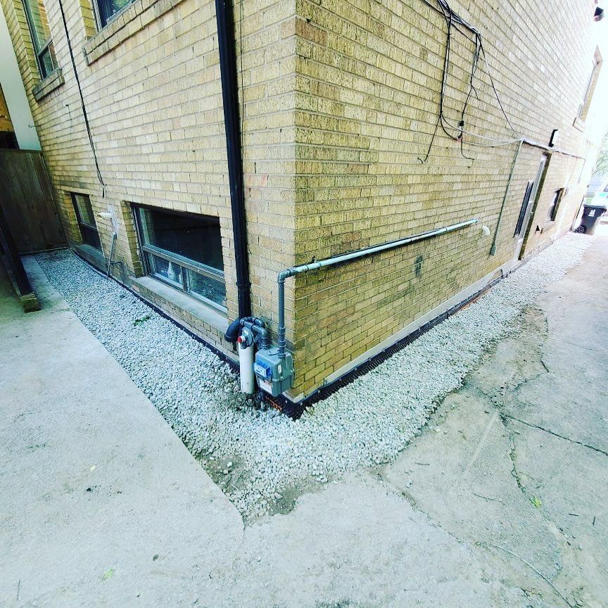 A brick building with a drain on the side of it