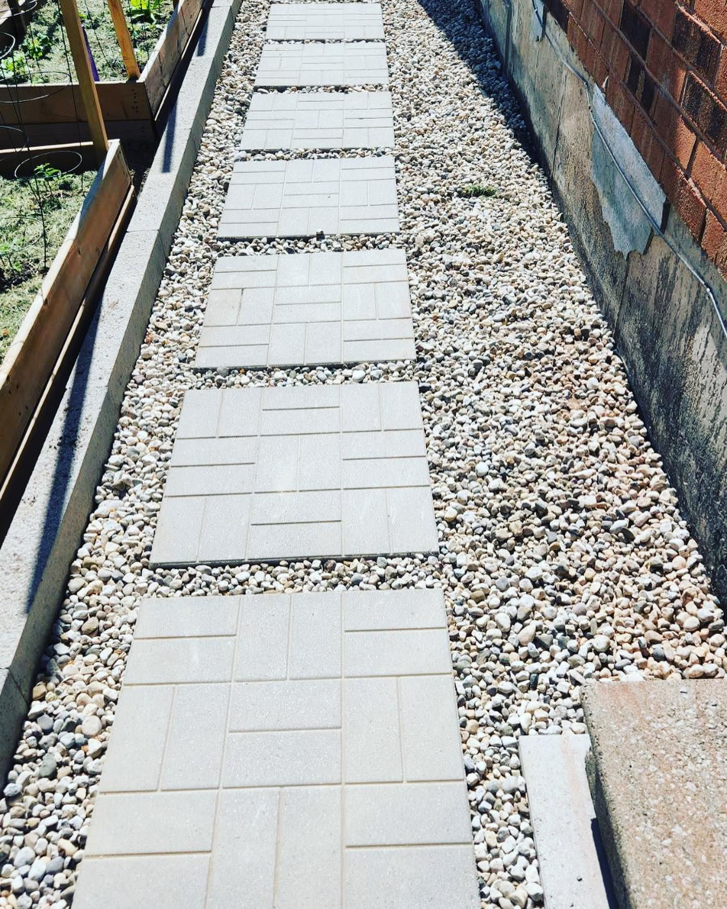 A walkway made of bricks and gravel next to a brick wall