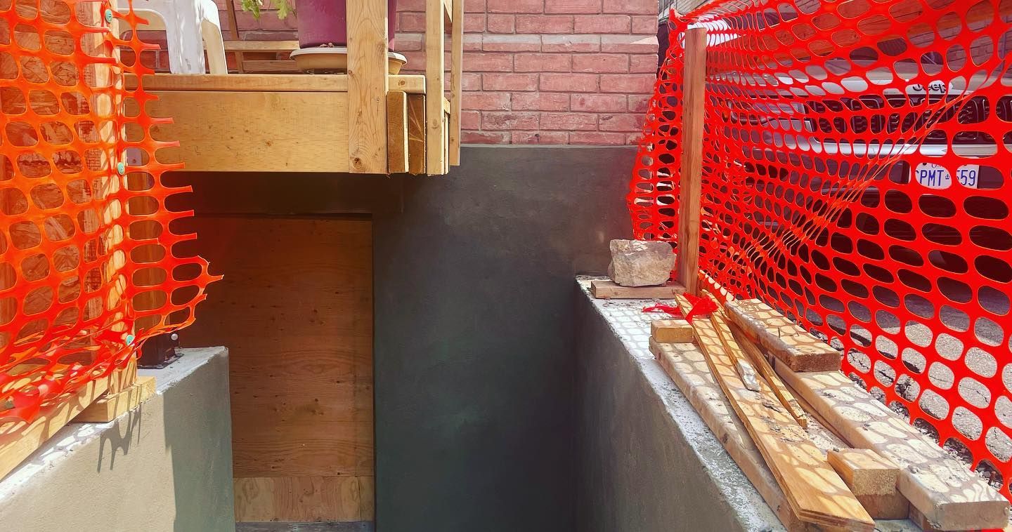 A construction site with a fence and a brick wall.