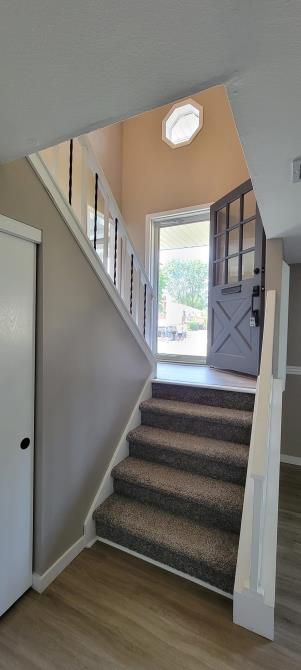 Staircase leading to an open front door with daylight and beige walls inside a home
