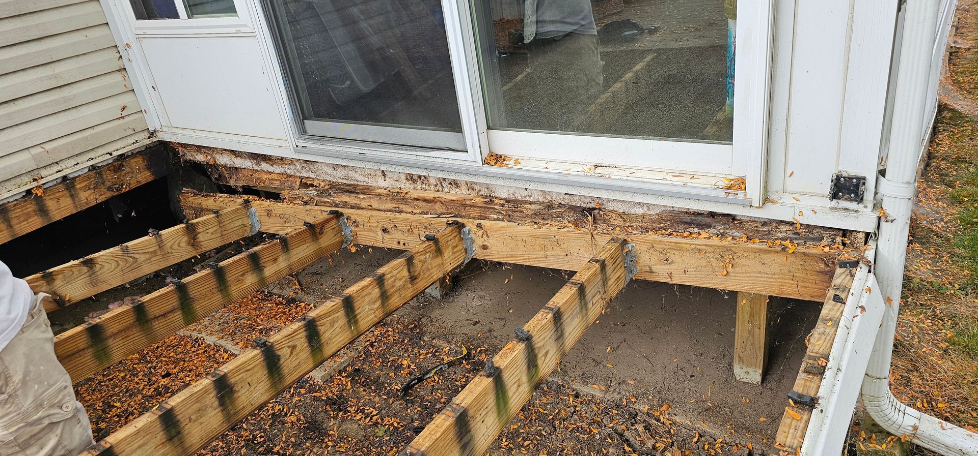 Damaged wooden steps and landing outside a house, with rotten boards and exposed framing.
