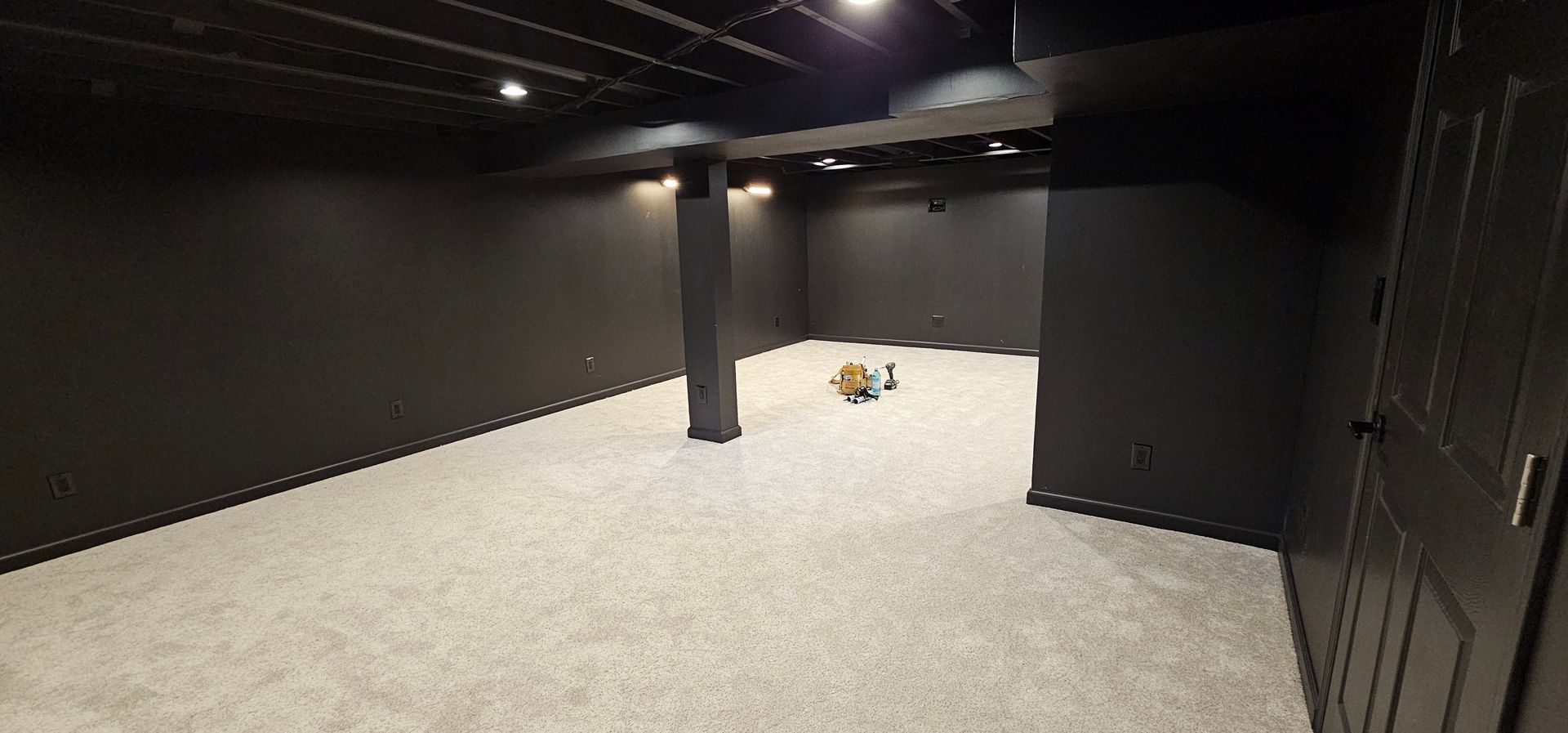 Empty black-painted room with carpeted floor and a small toy in the center