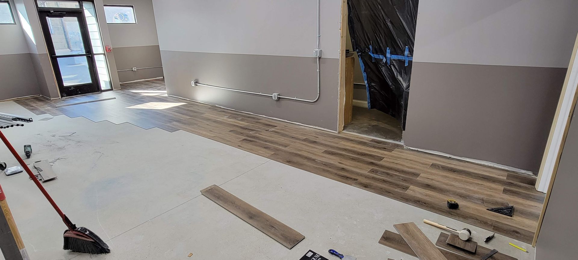 Renovated room with bare floors, exposed walls, tools, and flooring materials in progress