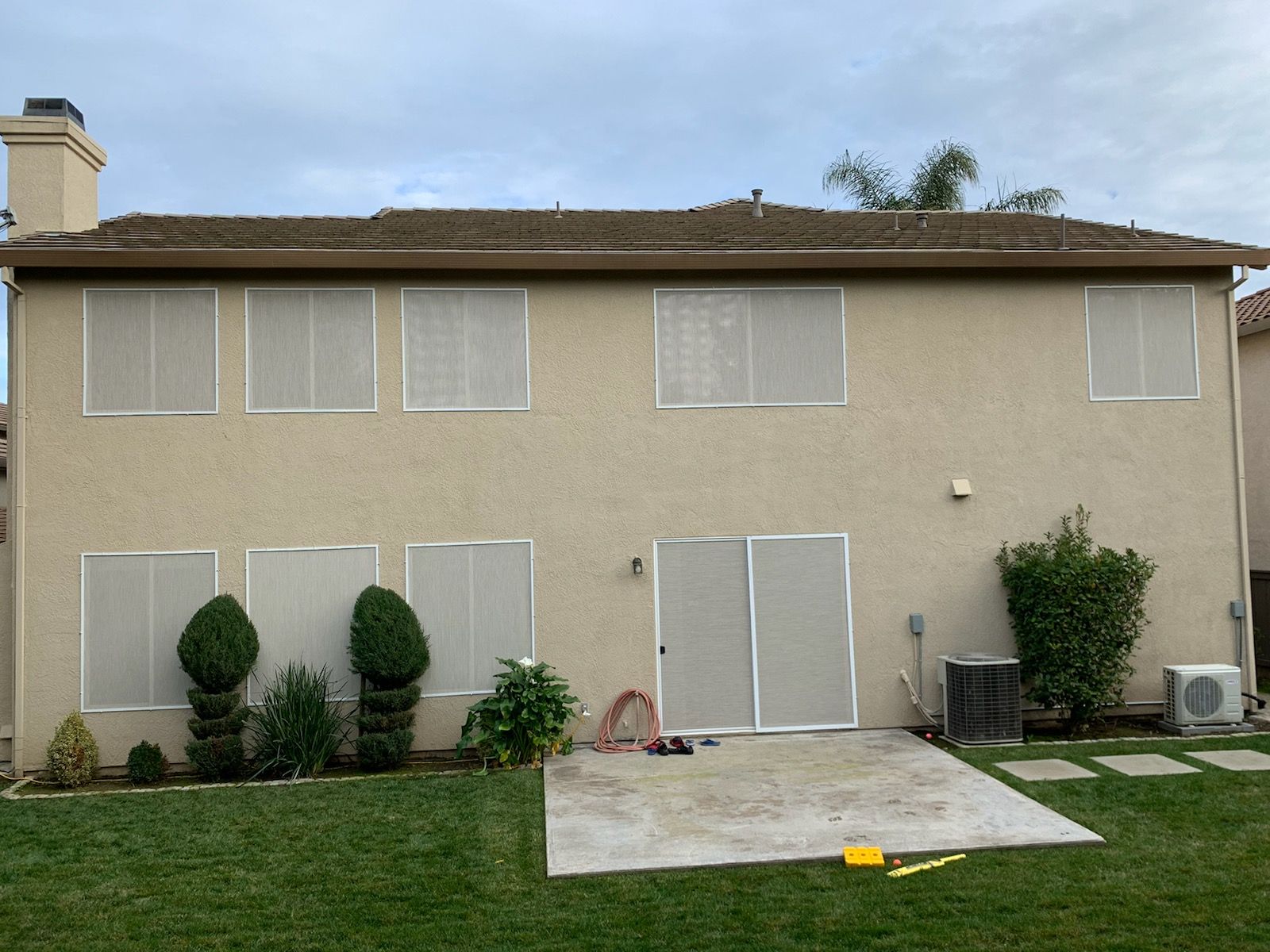 The back of a house with a lot of windows and a lawn in front of it.