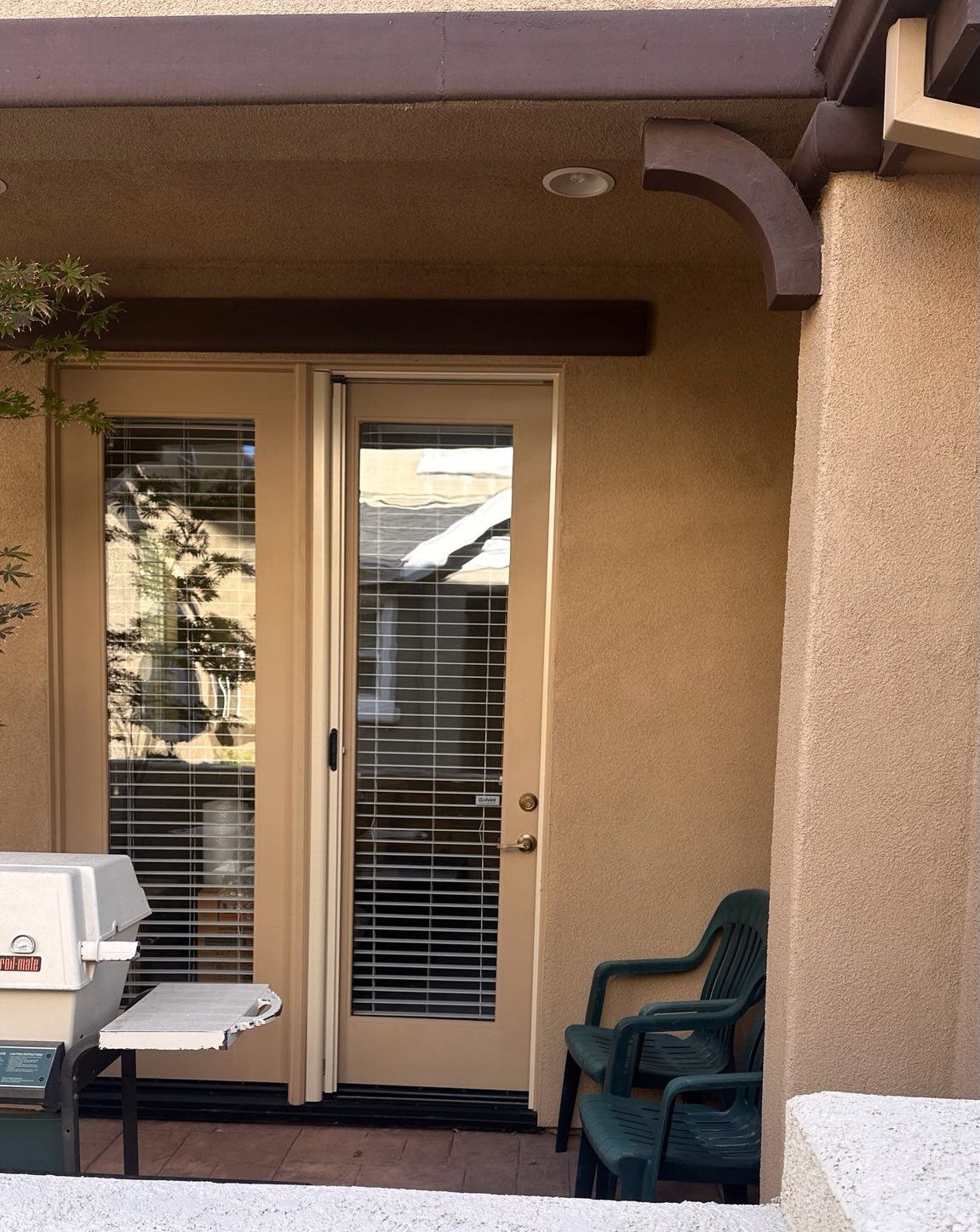 A screen door is open to a backyard with a house in the background.