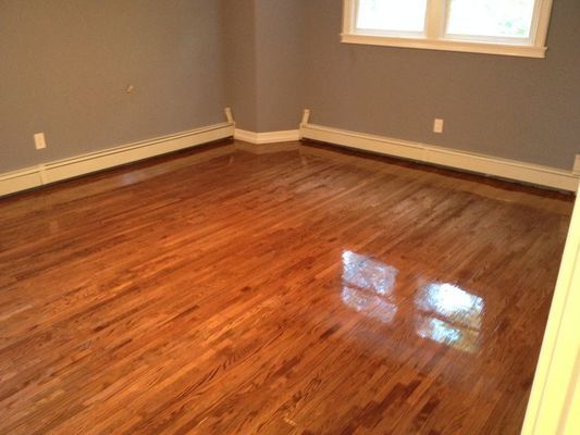 An empty room with hardwood floors and gray walls.