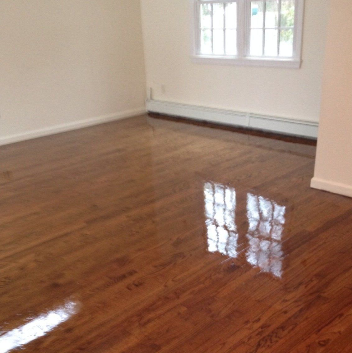 An empty room with hardwood floors and white walls