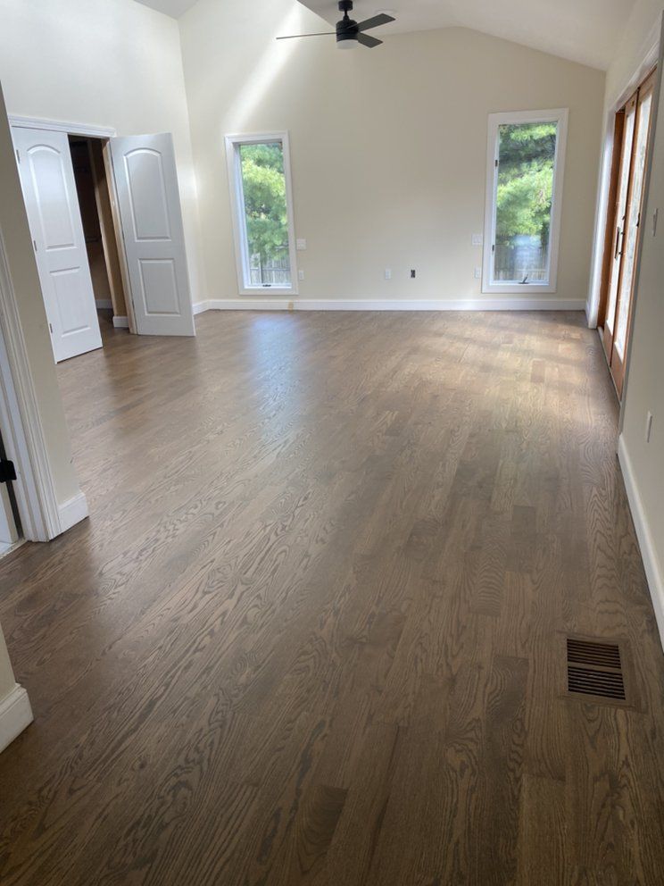 An empty living room with hardwood floors and a ceiling fan.