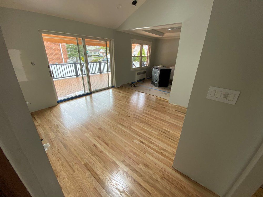 A living room with hardwood floors and sliding glass doors leading to a balcony.