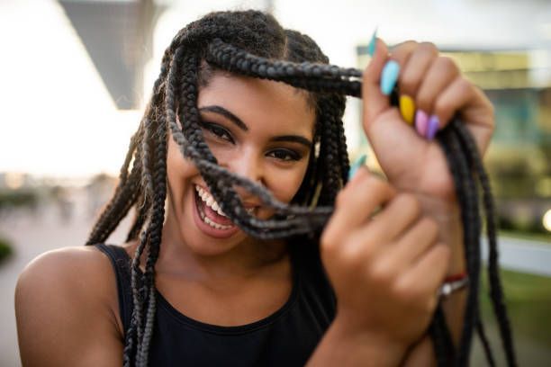 A Woman With Braids Is Holding A Rope In Her Hands And Smiling | Fayetteville, NC | Fatouisa African Braiding