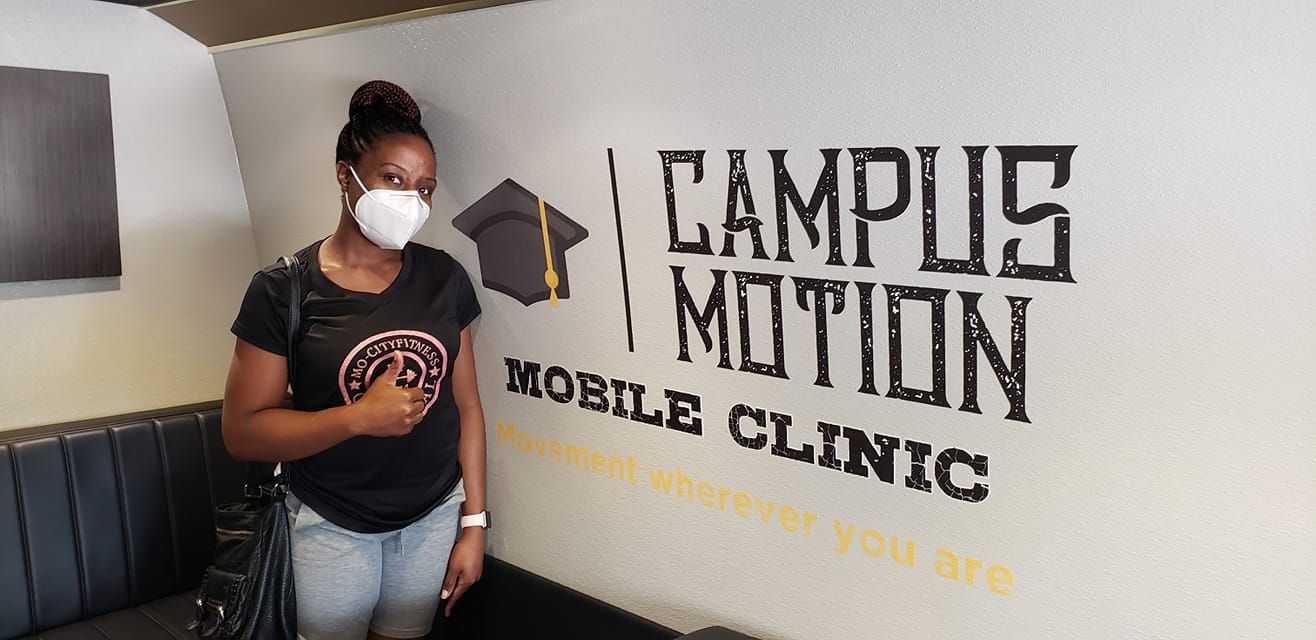 A woman standing beside campus motion logo representing our mobile clinic, which is dedicated to providing Enhanced Quality of Life by restoring physical function and offering emotional support to improve overall well-being and quality of life.