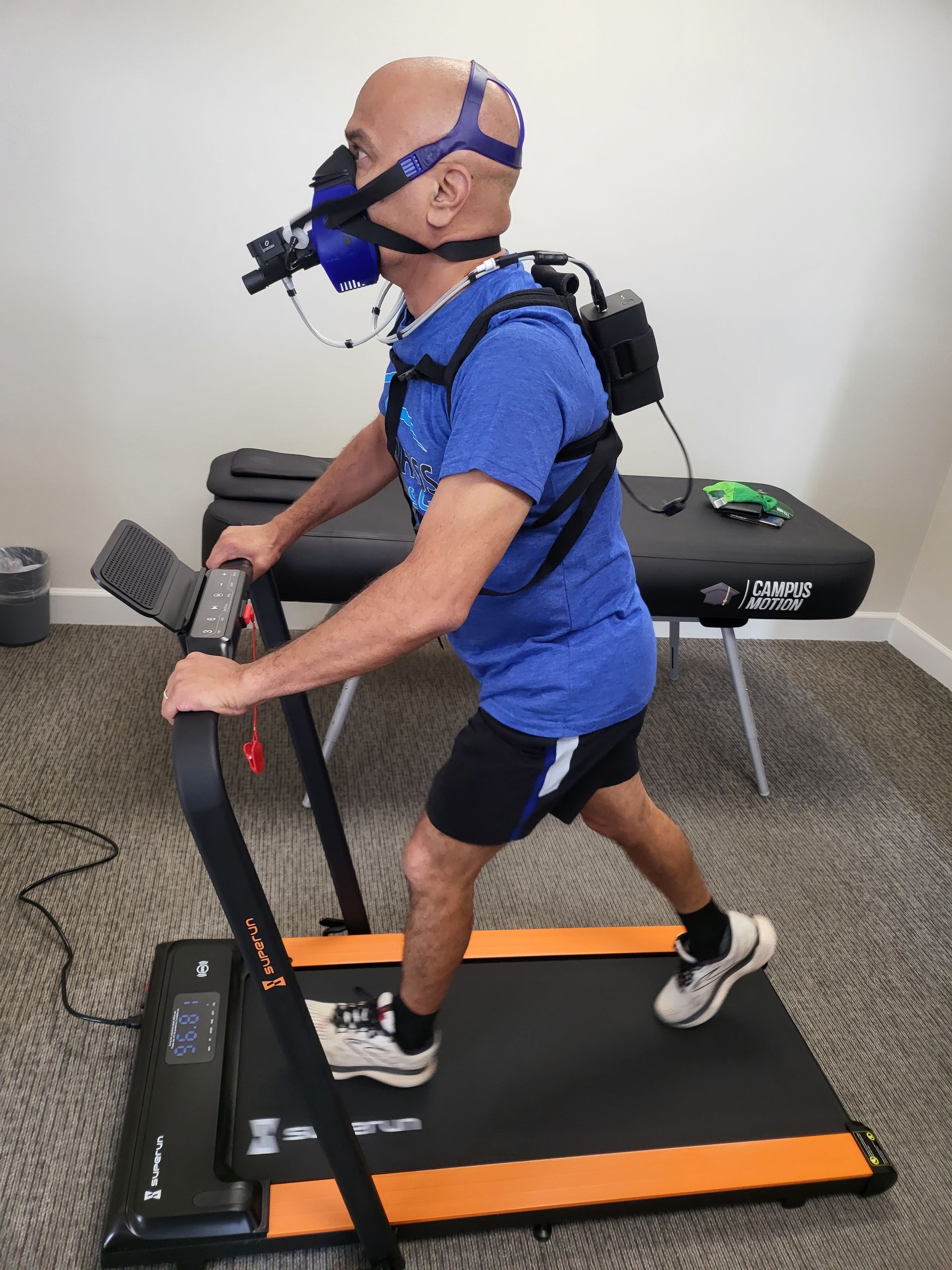 A man running on a treadmill with a metabolic breath analyzer, illustrating the use of VO2 Max data to create Optimized Training Programs. These personalized regimens maximize workout efficiency and help achieve goals such as endurance enhancement, athletic performance improvement, or weight loss, expediting progress.