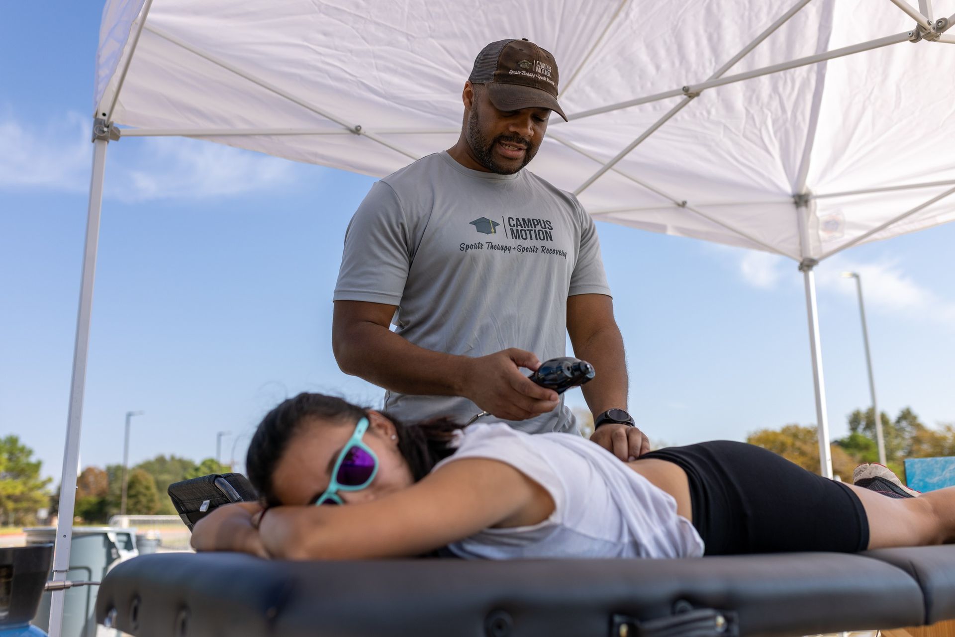 Okon Antia of Campus Motion conducting physical therapy treatment on a patient as part of Enhanced Athletic Performance efforts, utilizing assisted stretching to enhance flexibility, agility, and injury prevention for athletes.