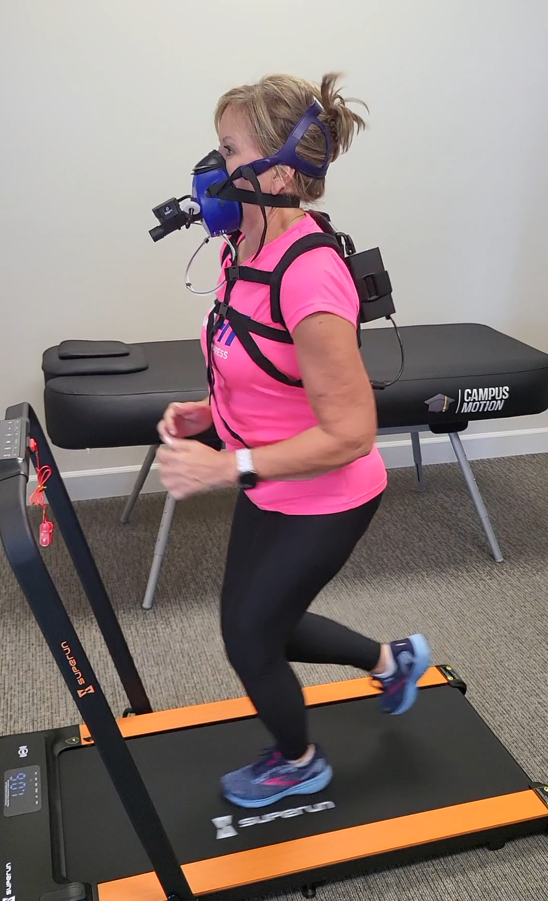 A woman running on a treadmill during VO2 Max Testing with the aid of a PNOE device, assessing her cardiovascular fitness and optimizing her workout plan for improved performance and health.