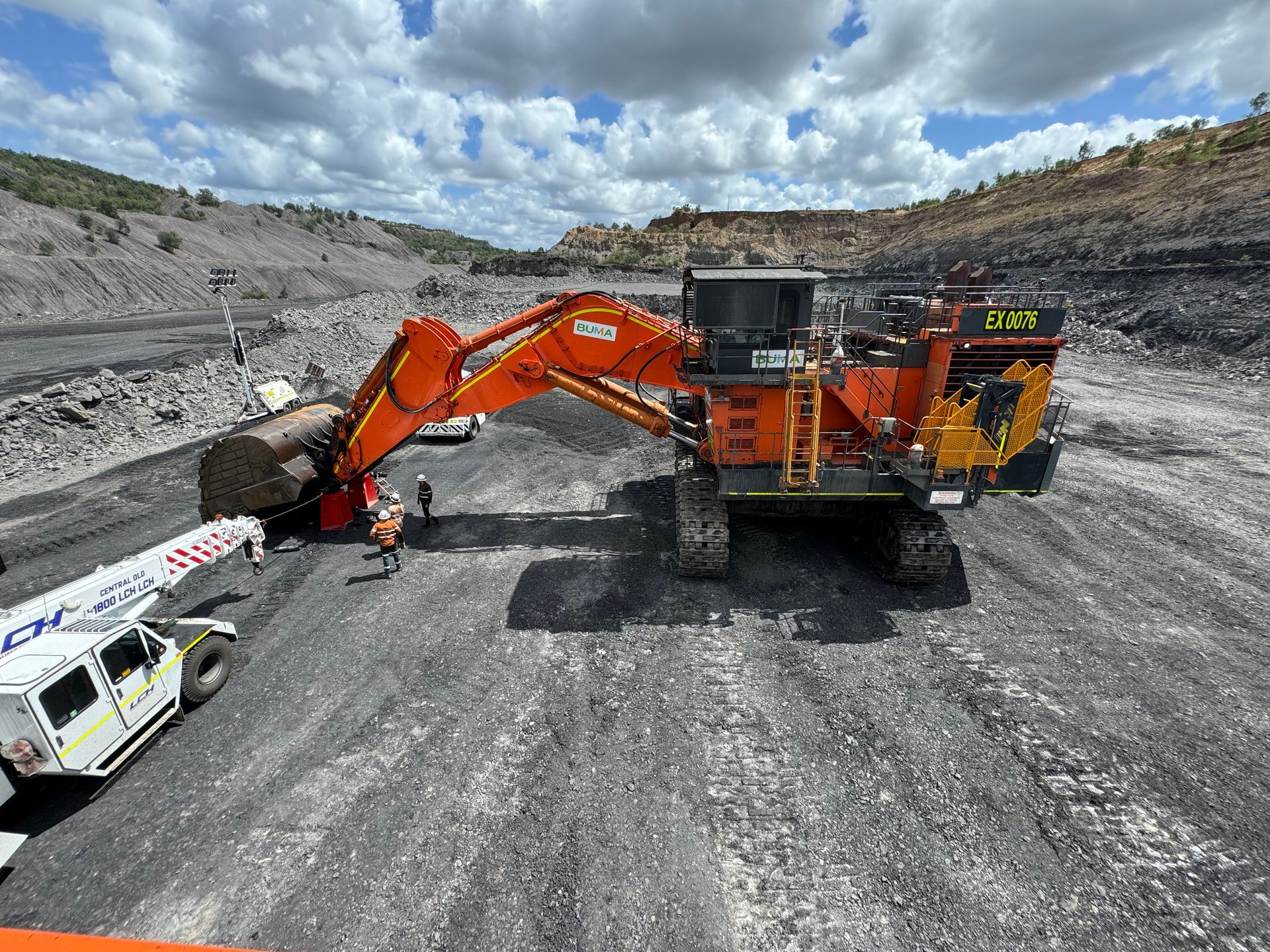 Orange excavator loading a dump truck in a gray open-pit quarry under cloudy skies — Resurge Diesel & Fabrication Pty Ltd In Balnagowan, QLD