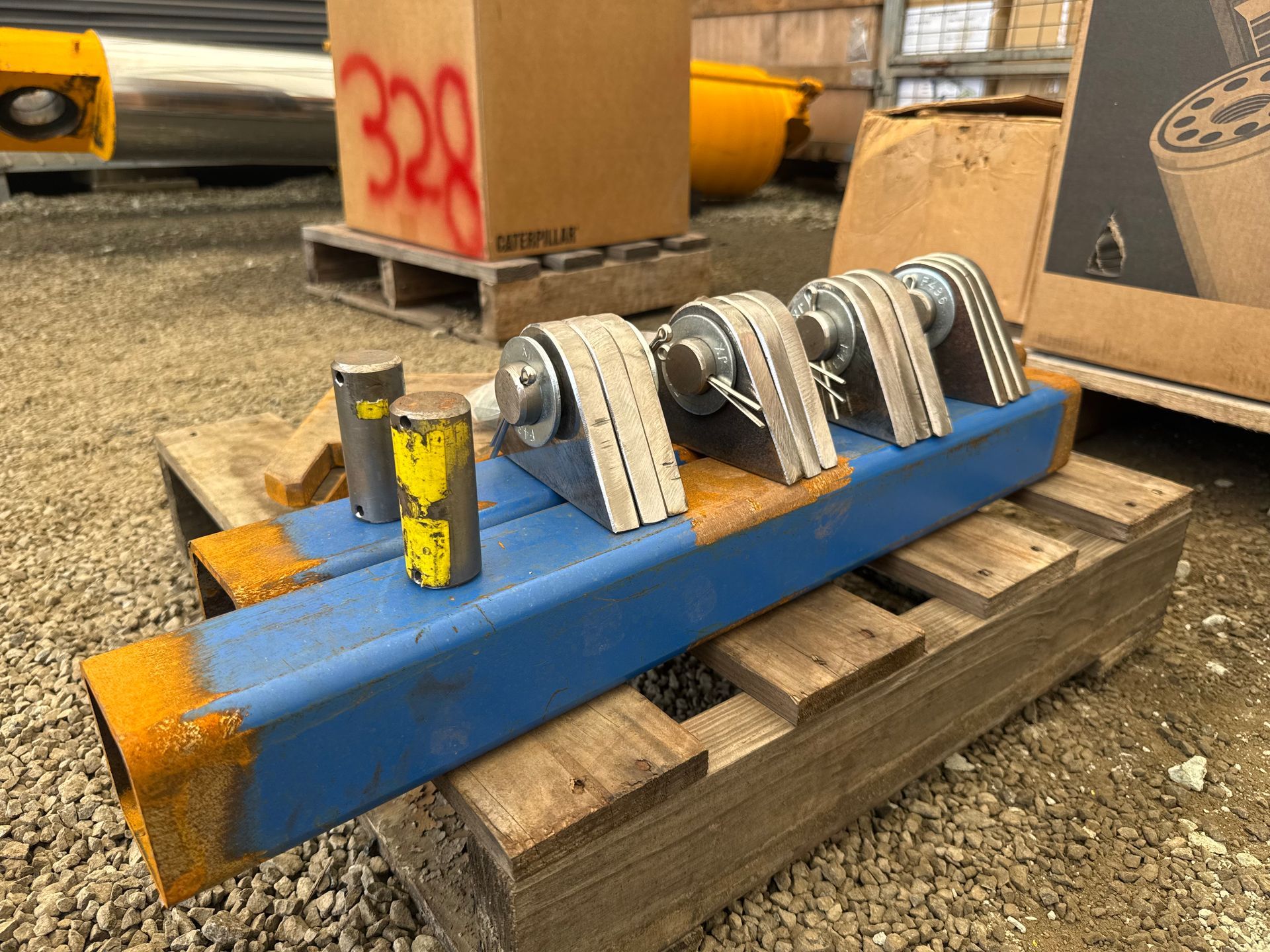 Blue industrial metal assembly with rollers and yellow caps sitting on wooden pallets outdoors — Resurge Diesel & Fabrication Pty Ltd In Balnagowan, QLD