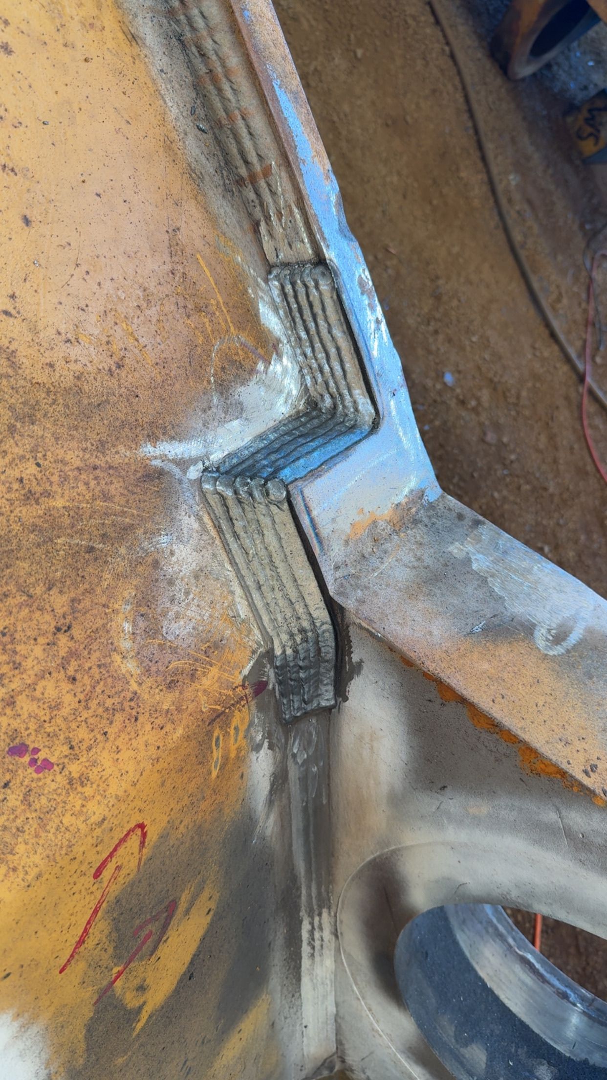 Close-up of a metal bracket and seam on a weathered yellow surface with a bolt at the bottom — Resurge Diesel & Fabrication Pty Ltd In Balnagowan, QLD