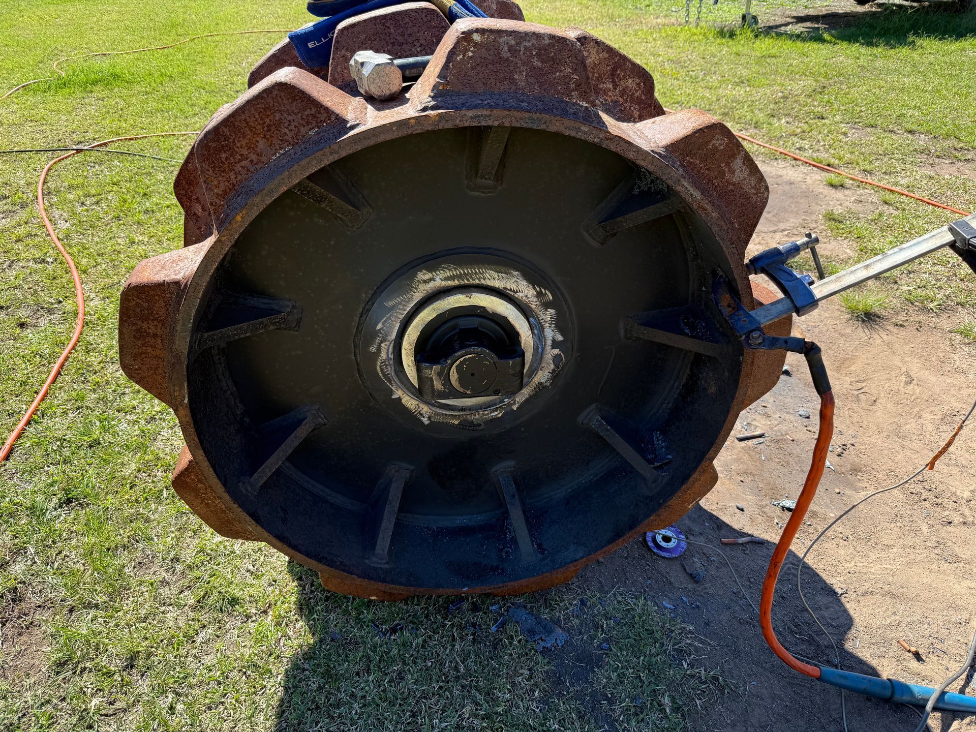 Large rusted metal drum or machine part on grass, with blue and orange cables attached — Resurge Diesel & Fabrication Pty Ltd In Balnagowan, QLD
