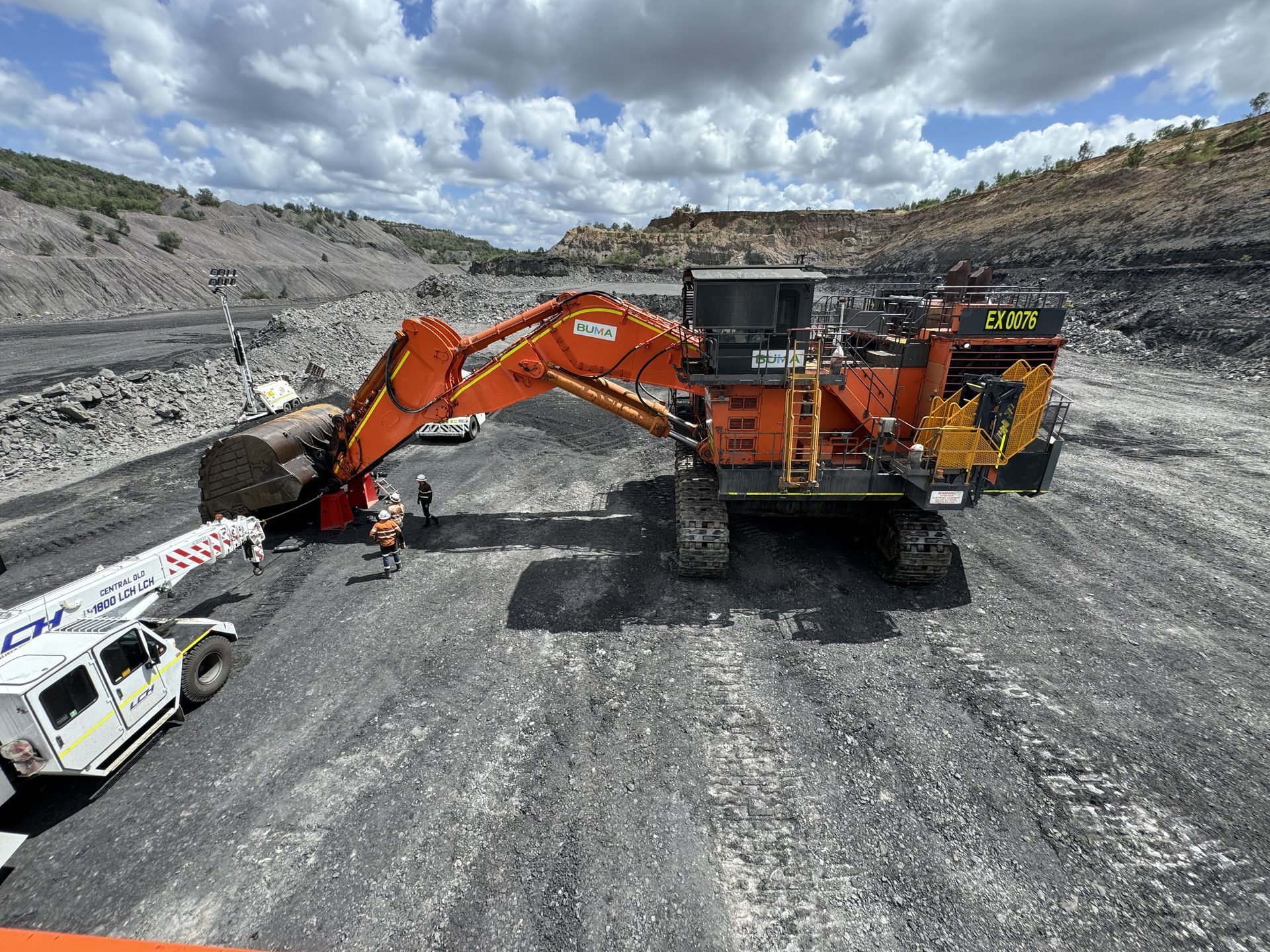 Orange excavator loading a white dump truck in a rocky quarry under cloudy skies — Resurge Diesel & Fabrication Pty Ltd In Balnagowan, QLD