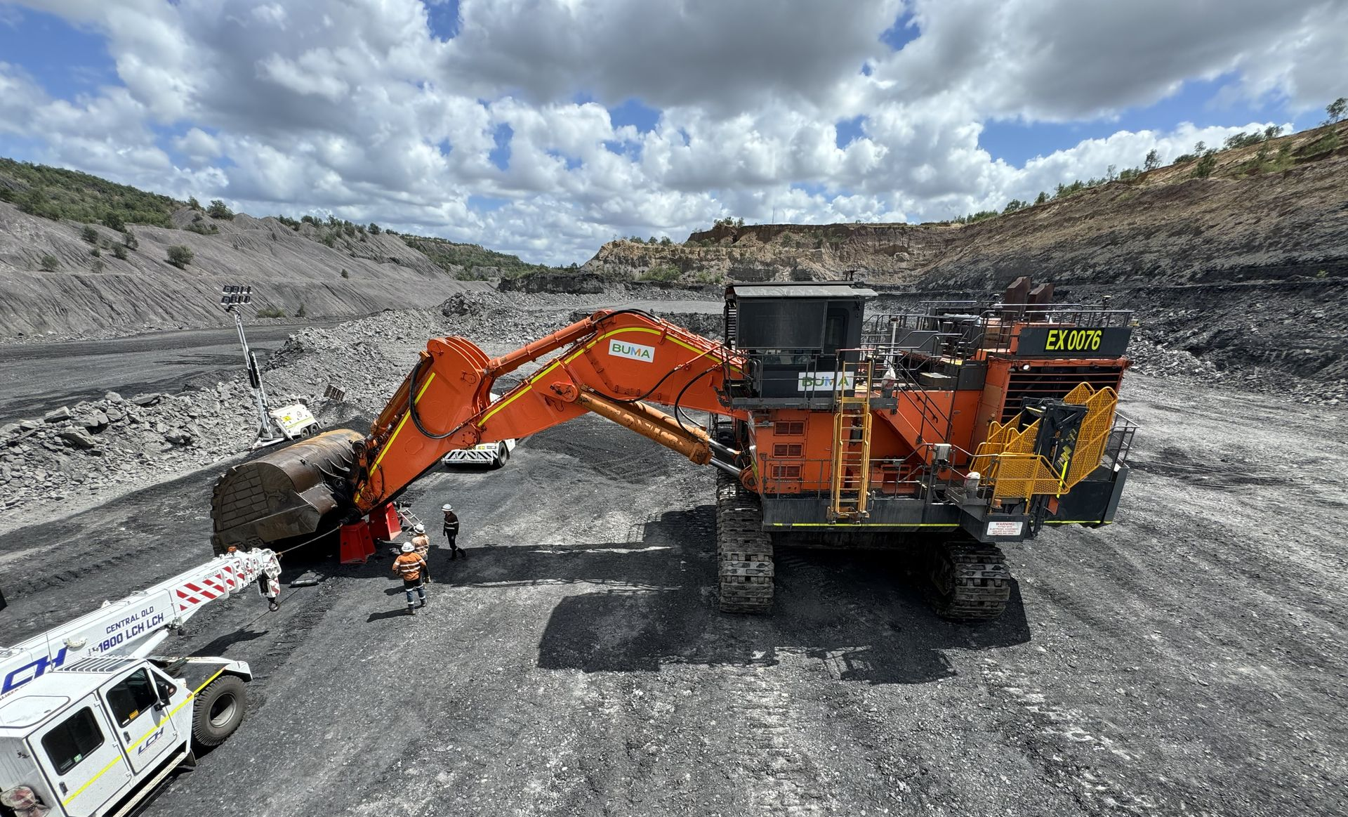 Orange excavator and dump truck working in a rocky open-pit mine under cloudy skies — Resurge Diesel & Fabrication Pty Ltd In Balnagowan, QLD