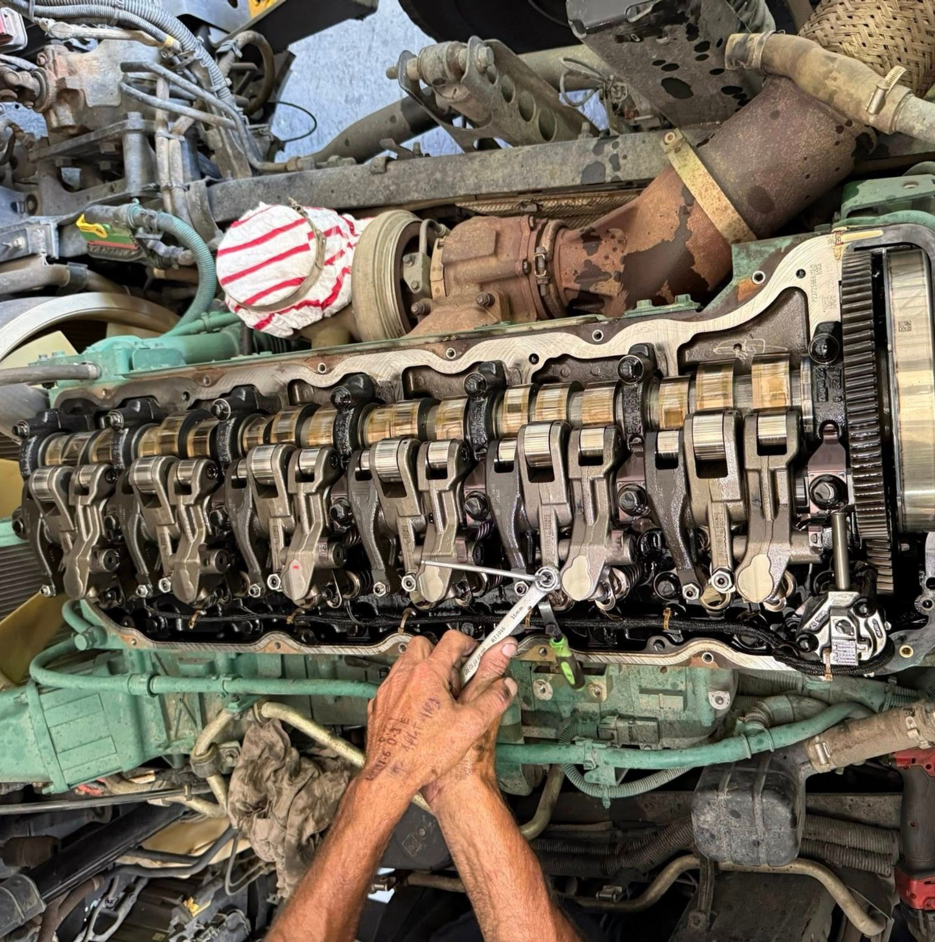 Mechanic inspecting exposed engine valve train with a tool in a workshop — Resurge Diesel & Fabrication Pty Ltd In Balnagowan, QLD