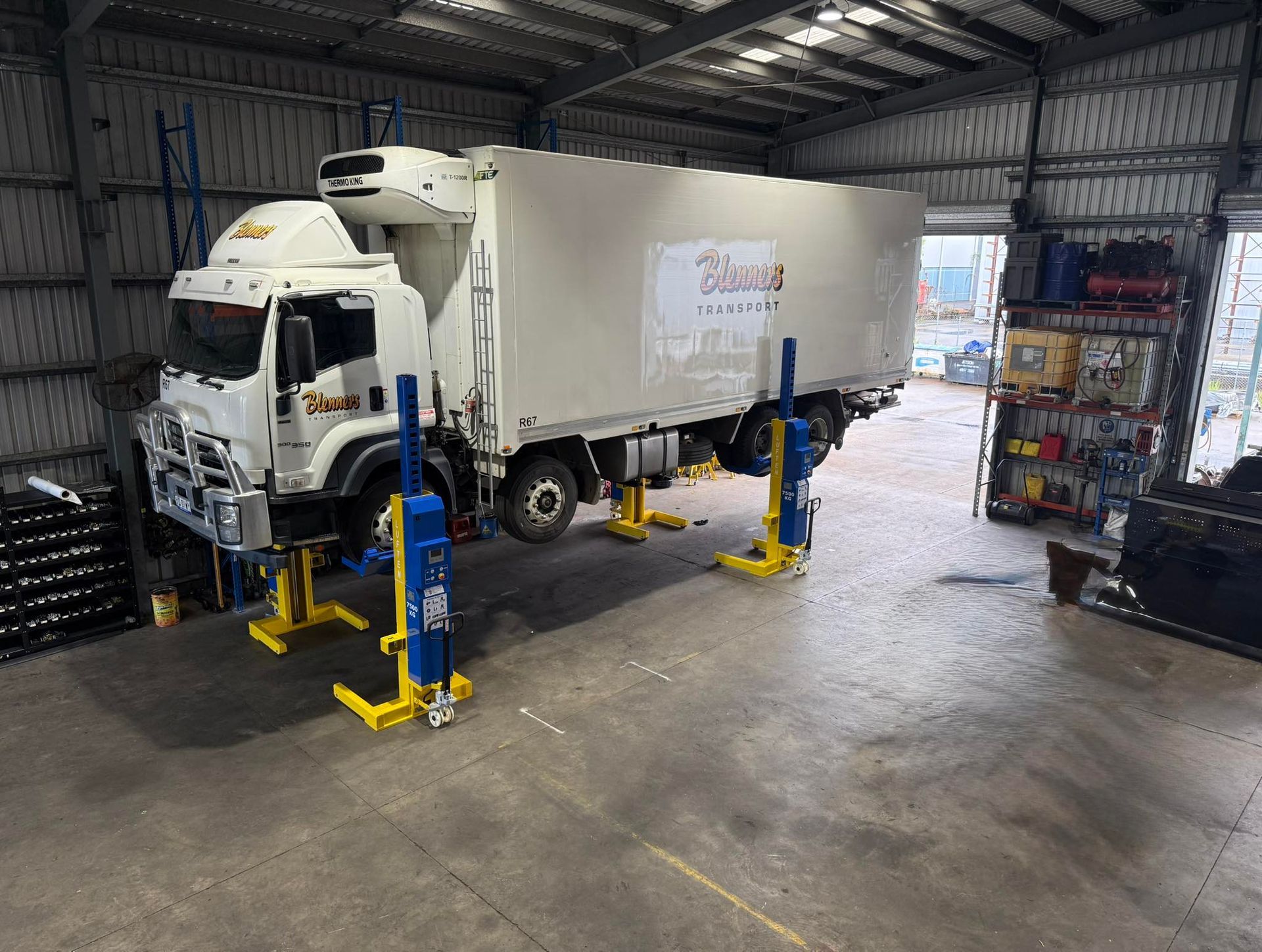 White box truck in a warehouse bay beside blue and yellow hydraulic lifts — Resurge Diesel & Fabrication Pty Ltd In Balnagowan, QLD