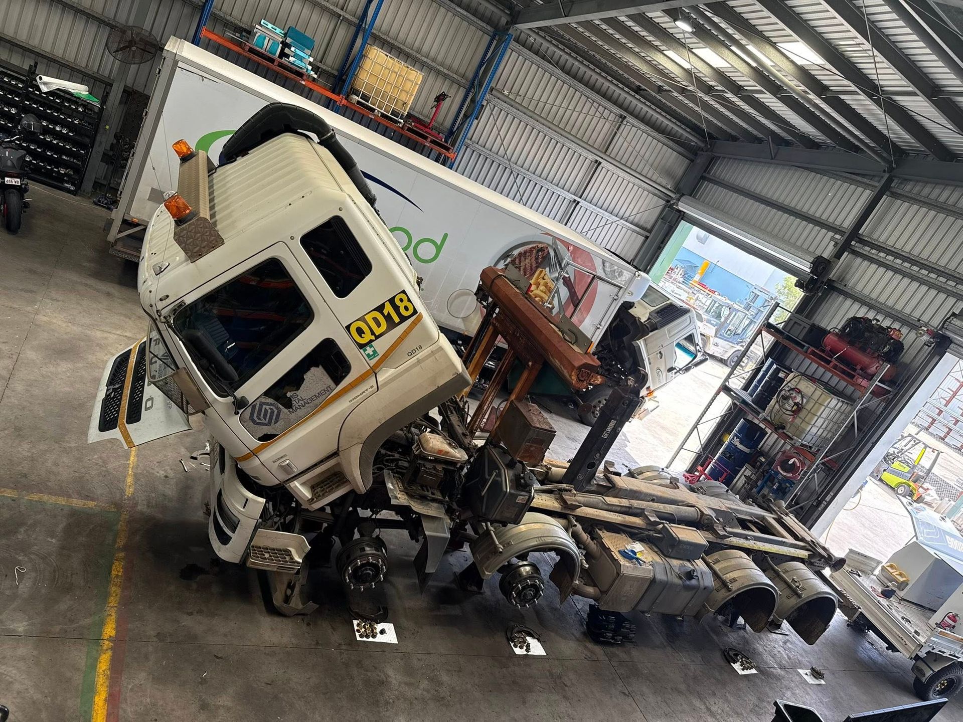 Damaged white truck cab in a warehouse, tilted on its side with debris and exposed chassis — Resurge Diesel & Fabrication Pty Ltd In Balnagowan, QLD