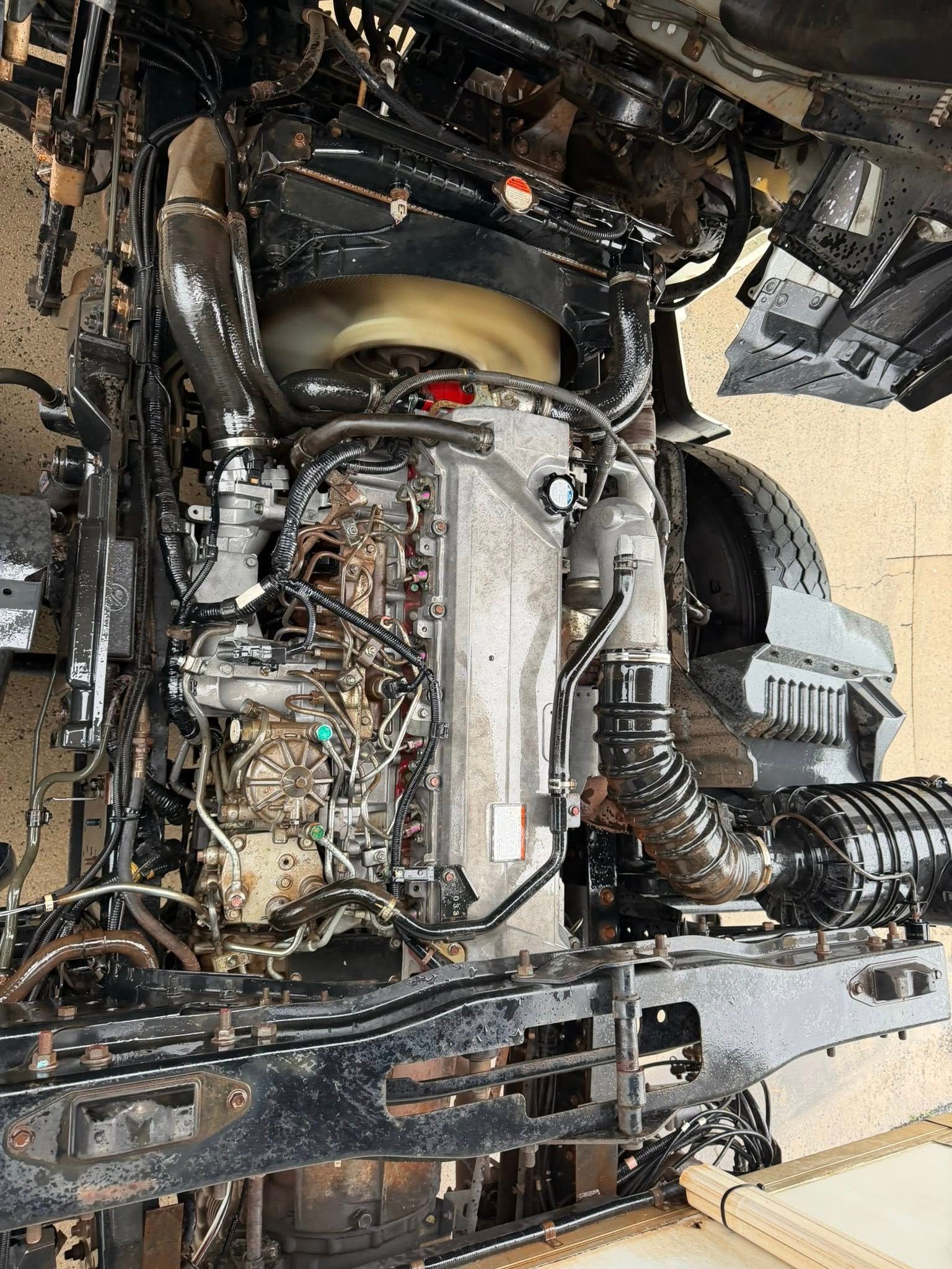 Engine compartment of a vehicle with exposed parts, wiring, and hoses in a workshop setting — Resurge Diesel & Fabrication Pty Ltd In Balnagowan, QLD