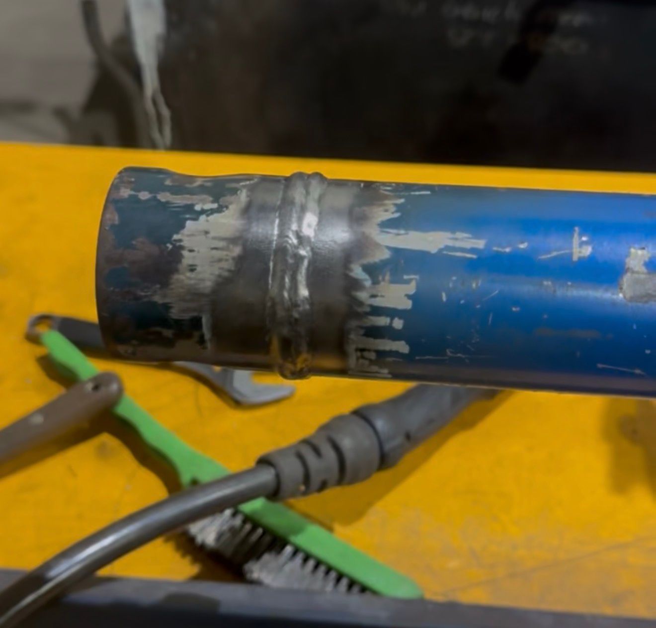 Blue metal pipe with a welded seam on a yellow workbench, with cables and tools nearby — Resurge Diesel & Fabrication Pty Ltd In Balnagowan, QLD
