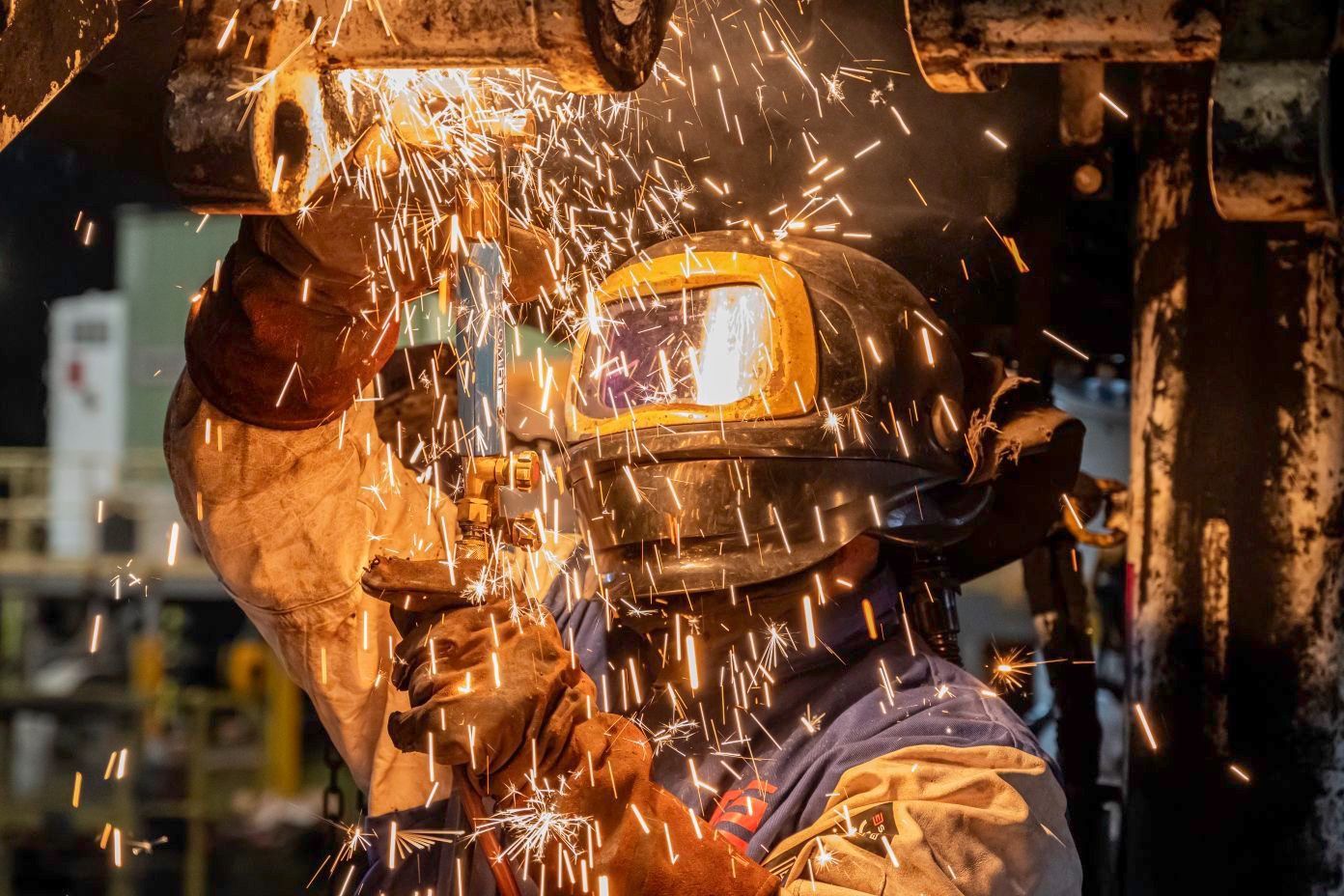 Welder in protective gear sparks flying from metal in a workshop — Resurge Diesel & Fabrication Pty Ltd In Balnagowan, QLD