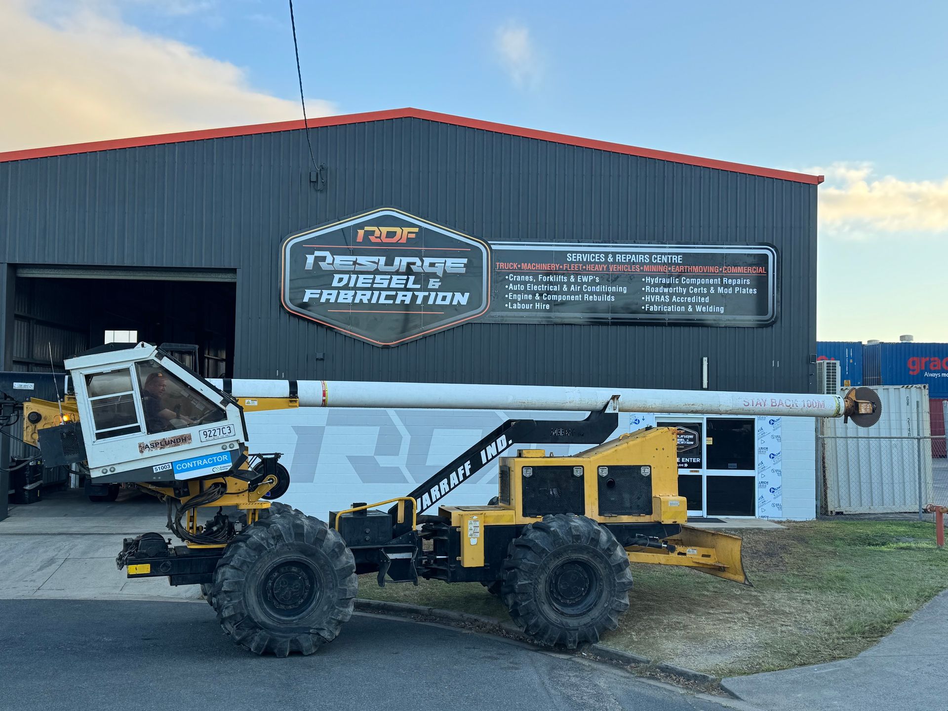 Yellow and black construction machine parked in front of a building — Resurge Diesel & Fabrication Pty Ltd In Balnagowan, QLD