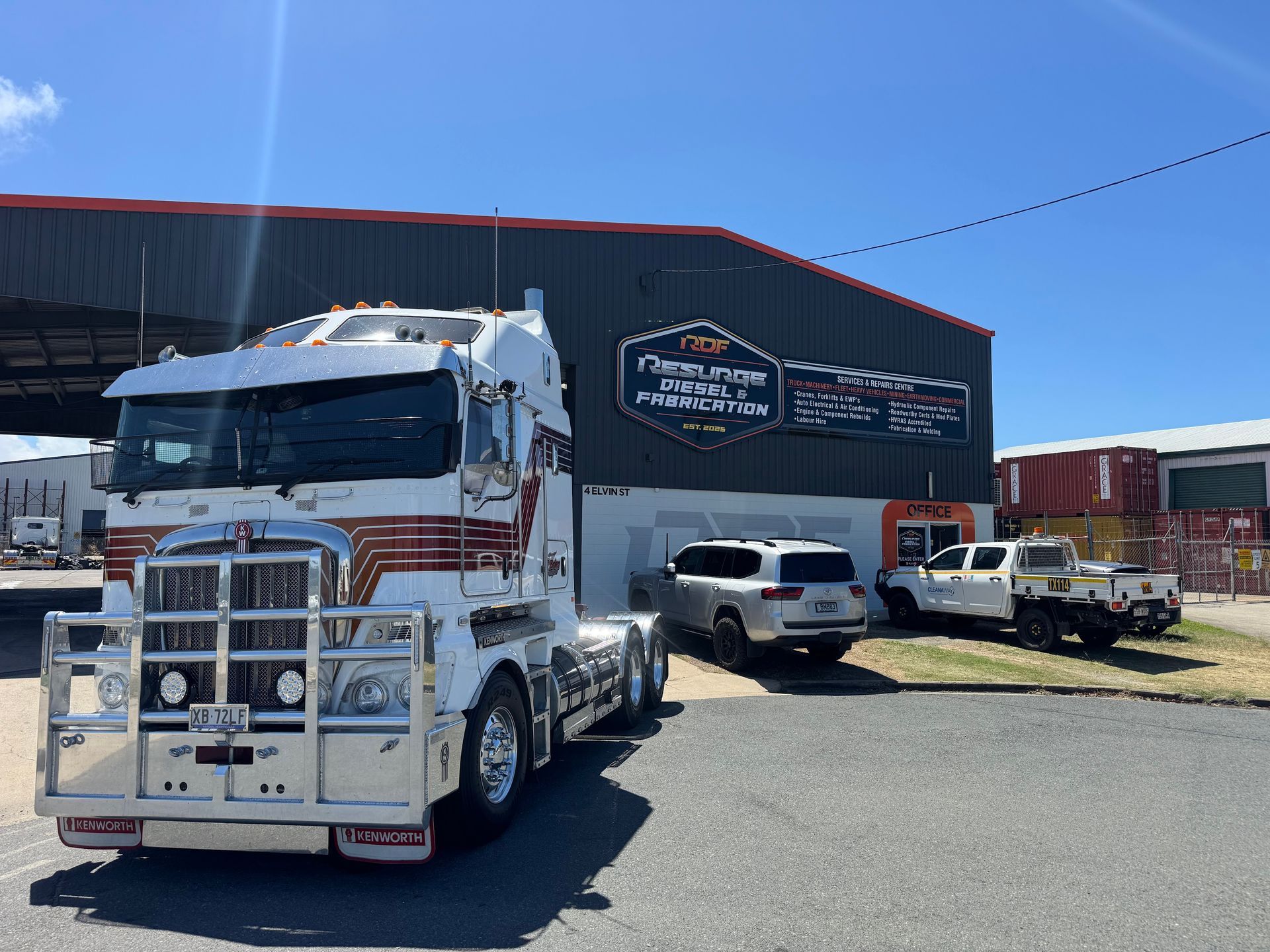 White semi-truck parked outside a black warehouse with several trucks and SUVs in the lot — Resurge Diesel & Fabrication Pty Ltd In Balnagowan, QLD